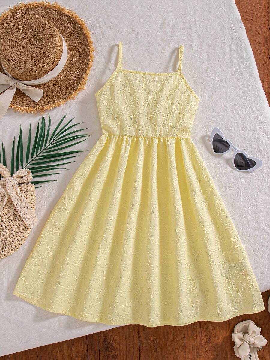 Tween girl wearing an apricot floral print sleeveless mini cami dress featuring spaghetti straps, a shirred high waist, flounce hem, and a bow back detail.