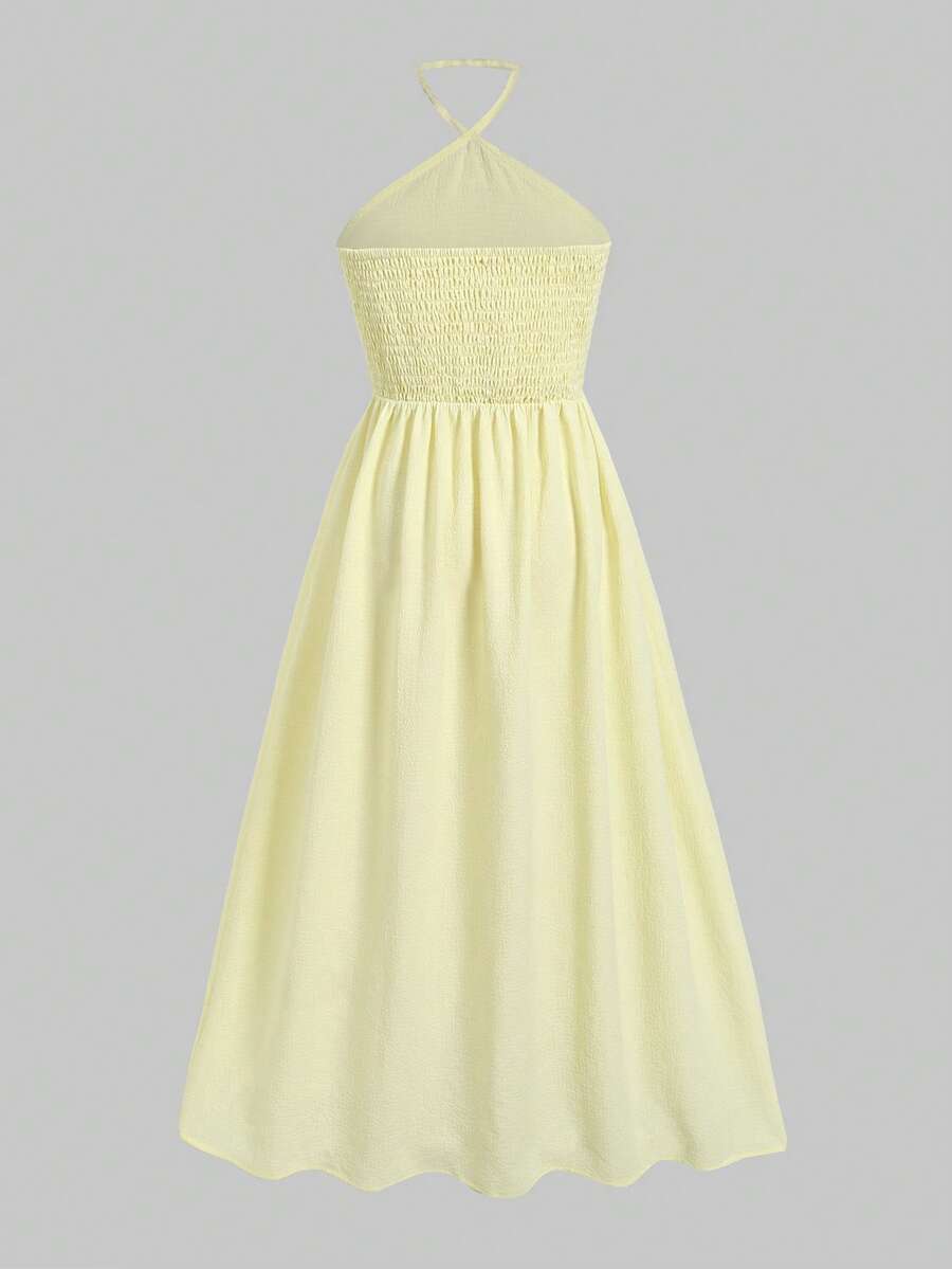 Tween girl yellow long halter dress with cutout waist, split detail, shirred textured fabric, sleeveless design, high waist, and flared hem for beach vacation wear.
