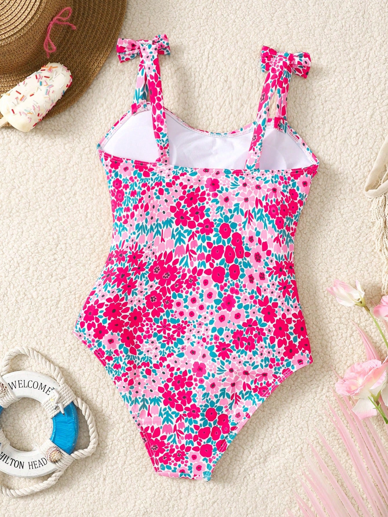 Tween girl floral print one-piece swimsuit with twist front, spaghetti straps, fitted shape, and multicolor all-over hibiscus-inspired pattern for beach and pool wear.