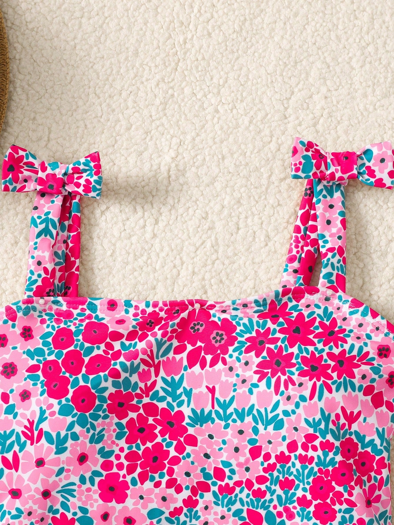 Tween girl floral print one-piece swimsuit with twist front, spaghetti straps, fitted shape, and multicolor all-over hibiscus-inspired pattern for beach and pool wear.