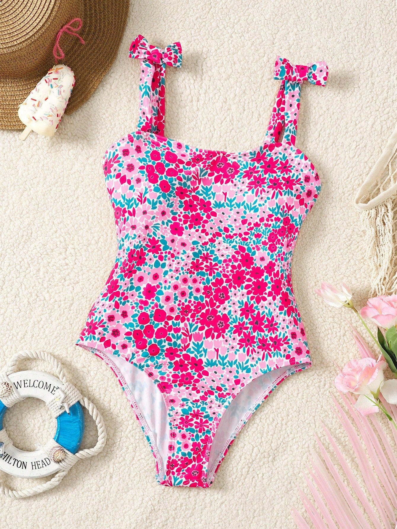 Tween girl floral print one-piece swimsuit with twist front, spaghetti straps, fitted shape, and multicolor all-over hibiscus-inspired pattern for beach and pool wear.