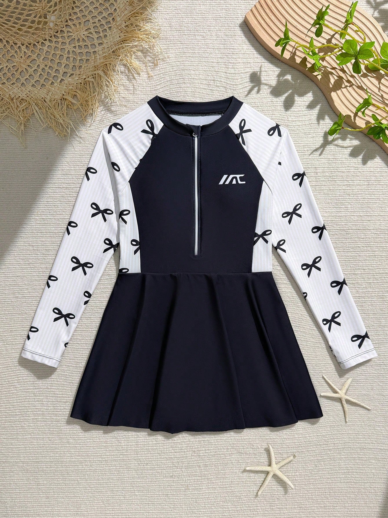 Tween girls one-piece swimsuit in black floral pattern with long sleeves, high neck, front zipper, and a skirt-style bottom.