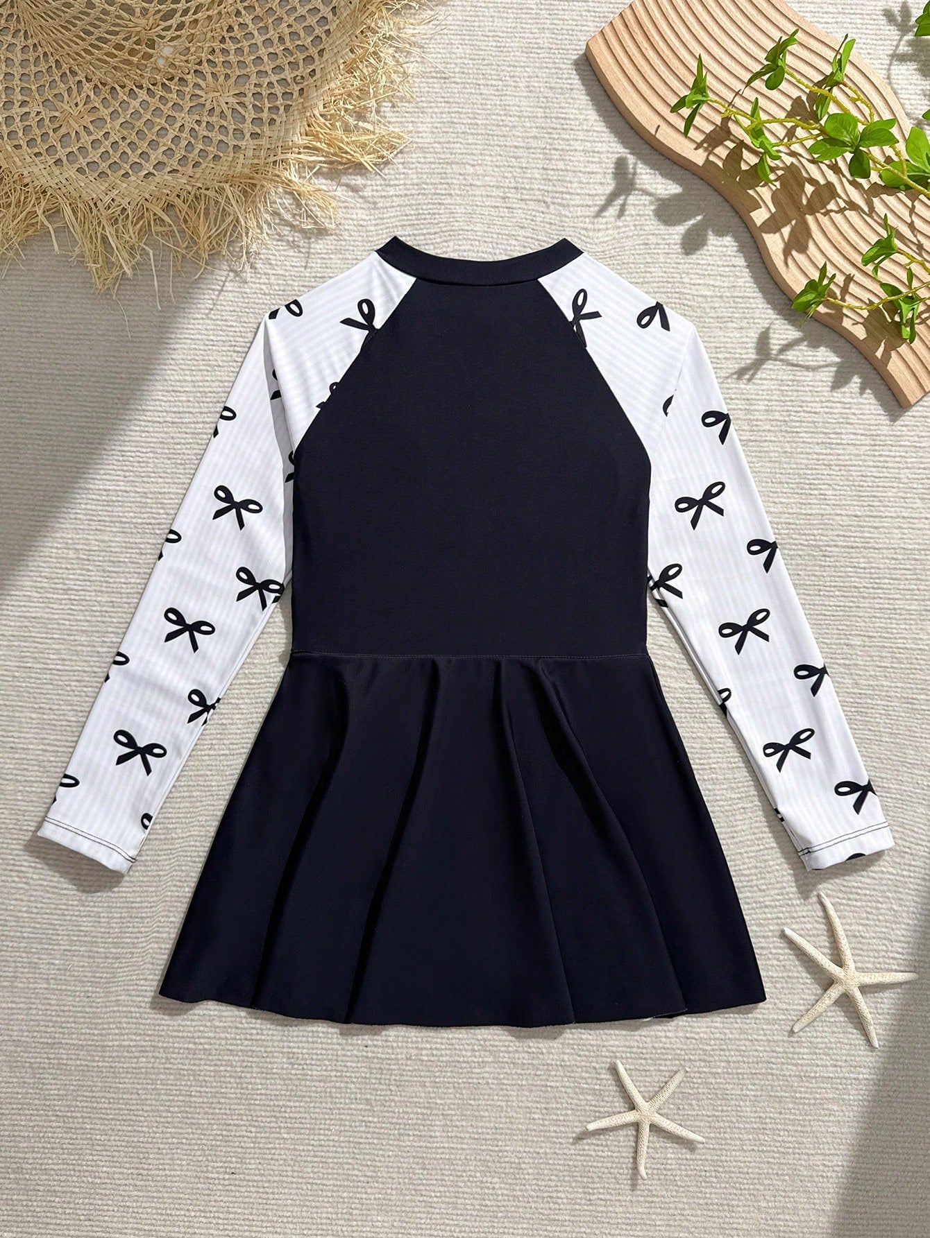 Tween girls one-piece swimsuit in black floral pattern with long sleeves, high neck, front zipper, and a skirt-style bottom.