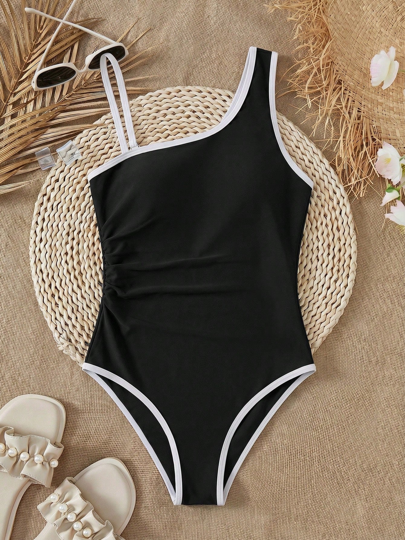 Tween girl one-piece swimsuit in brown polka dot geometric print with asymmetrical neckline, ruffle detail, cut-out design, and fitted mid-waist swim bottom.