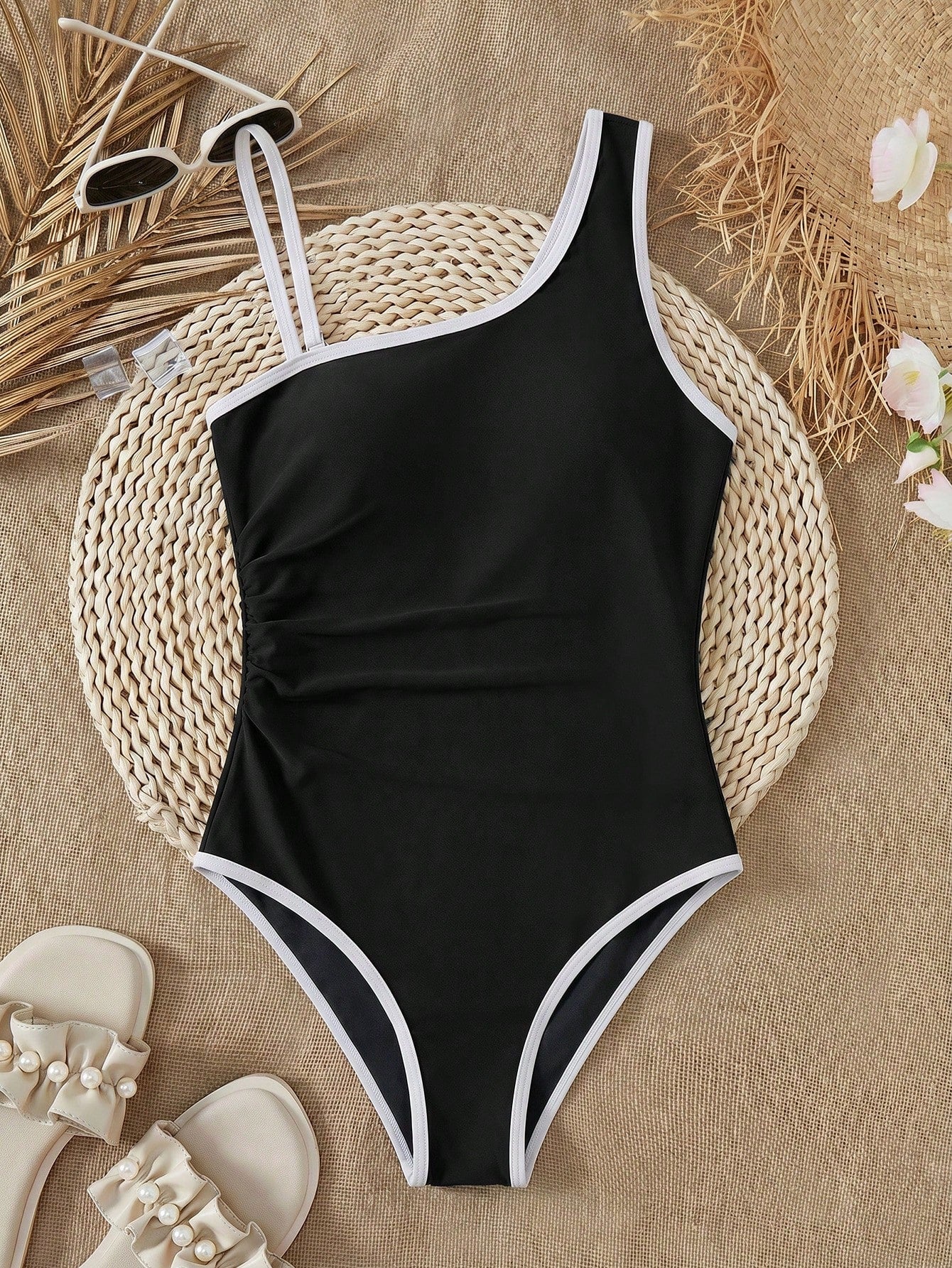 Tween girl one-piece swimsuit in brown polka dot geometric print with asymmetrical neckline, ruffle detail, cut-out design, and fitted mid-waist swim bottom.