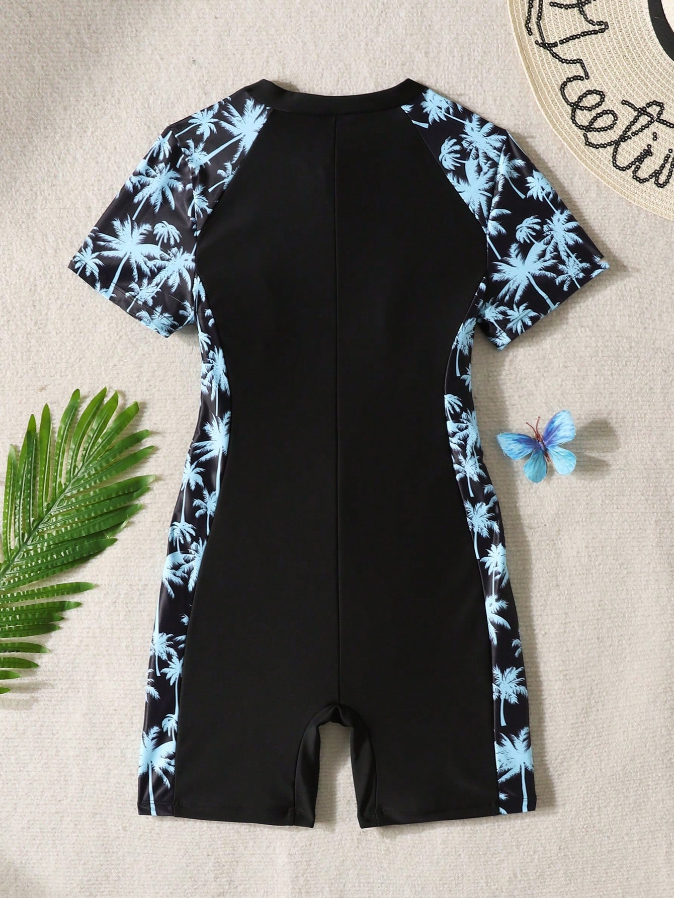 Black and white one-piece rashguard swimsuit for tween girls with short sleeves, high neck, zipper detail, fitted shape, and shorts-style bottom.
