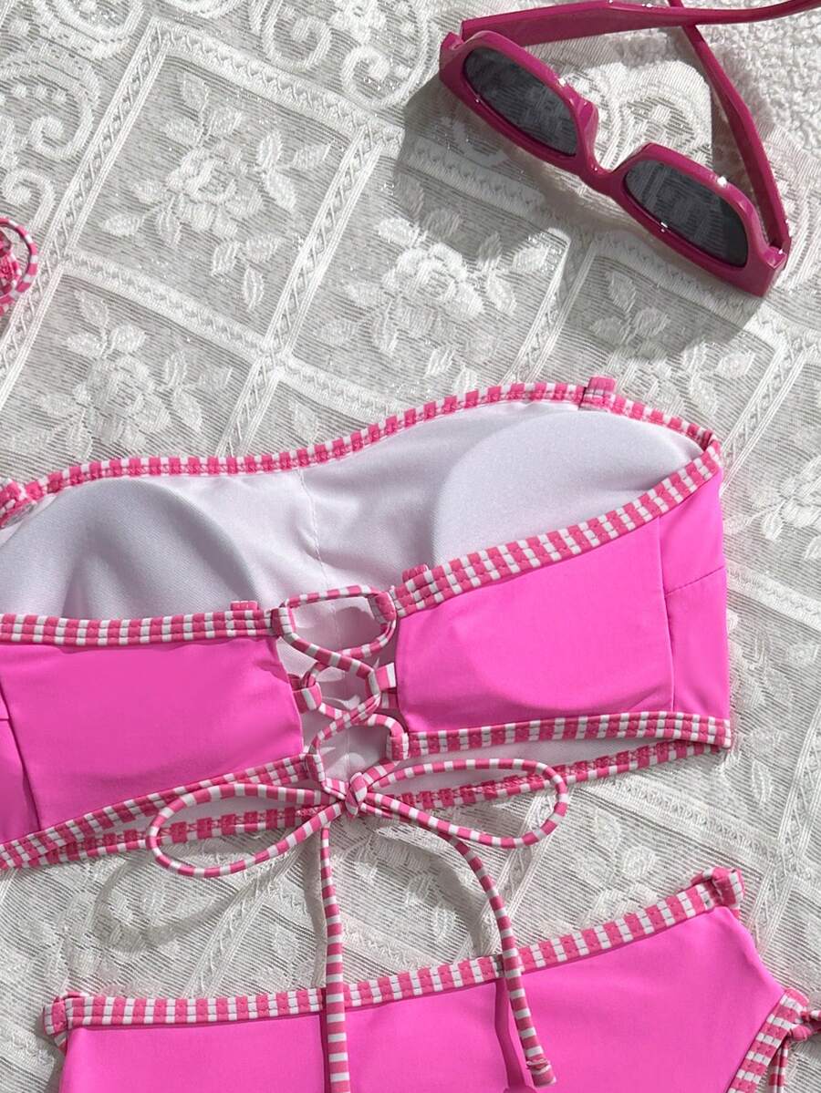 Women's hot pink split bikini set featuring a high waist tie-side bottom and a wireless bandeau top with criss cross details.