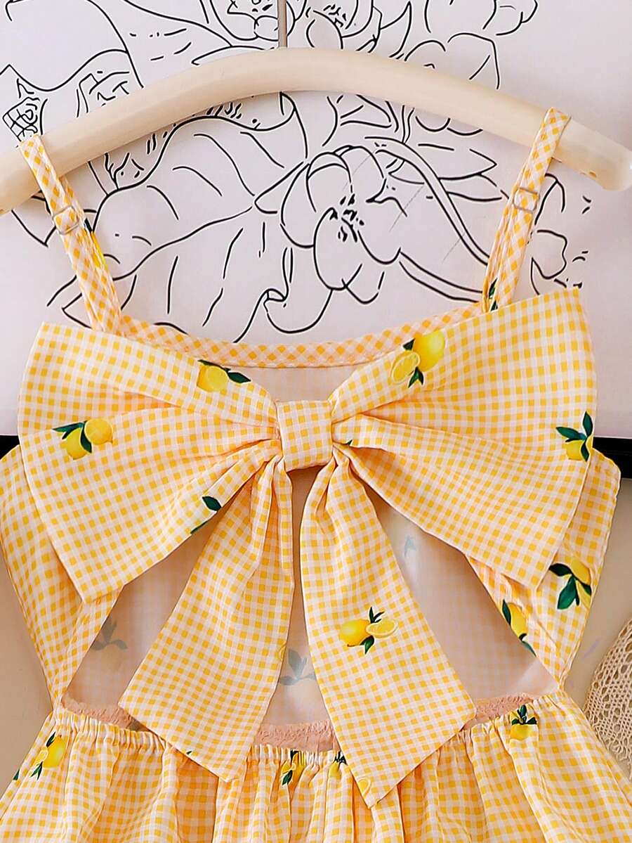 Tween girl wearing an apricot floral print sleeveless mini cami dress featuring spaghetti straps, a shirred high waist, flounce hem, and a bow back detail.