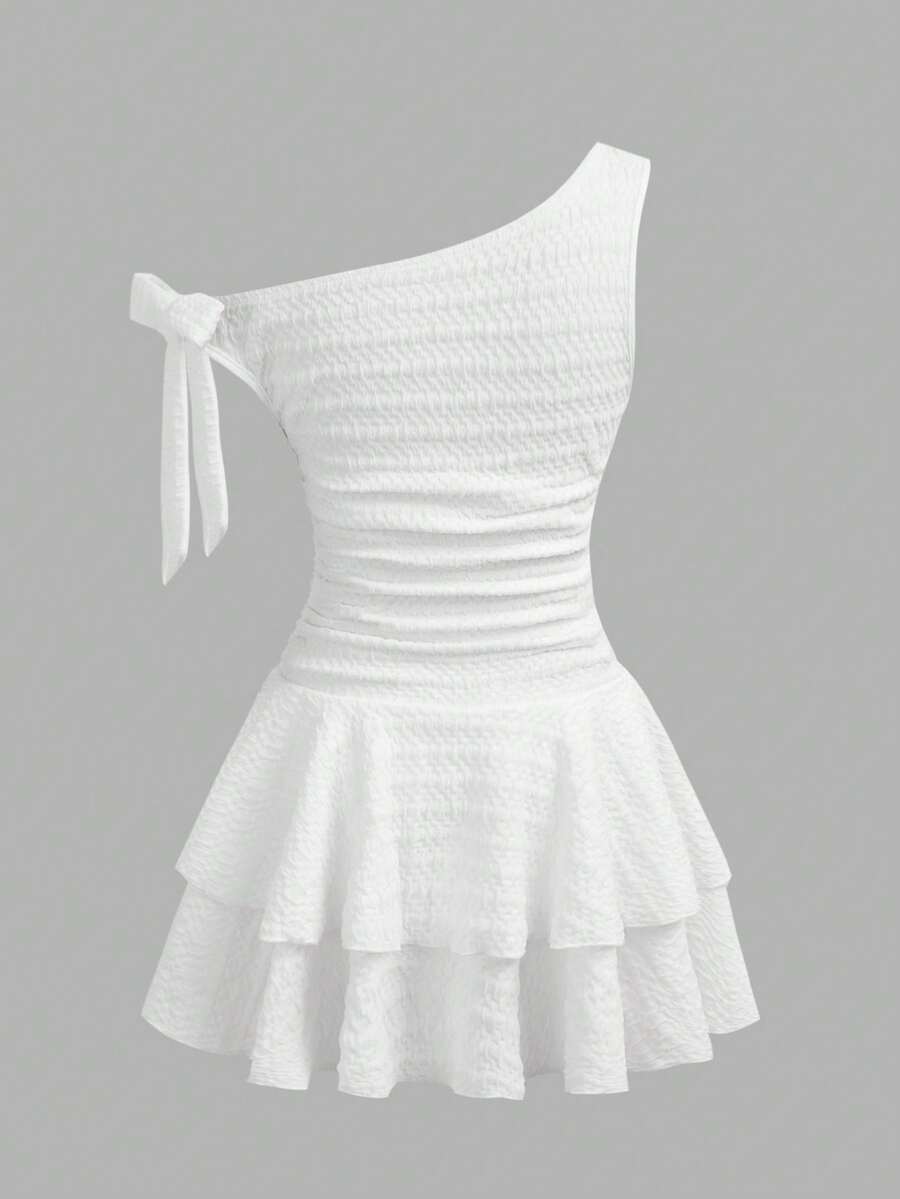 Tween girl wearing an apricot asymmetrical tiered sleeveless party dress with an A-line silhouette.