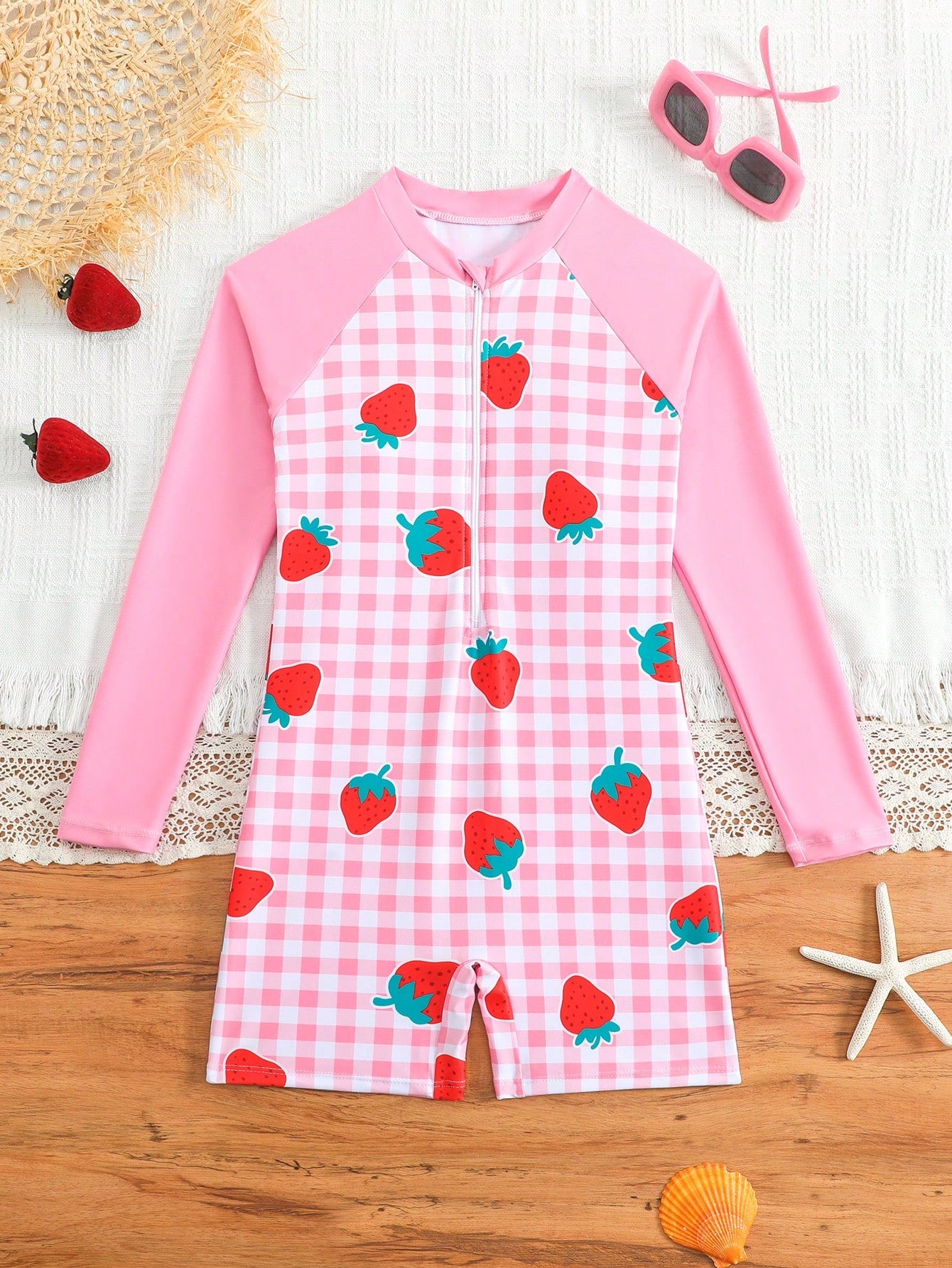 Tween girls one-piece swimsuit featuring a high neck, long sleeves, and shorts bottom, with a back zipper and strawberry plaid digital print on stretch knit fabric. Designed for swimming, vacation, and summer wear.