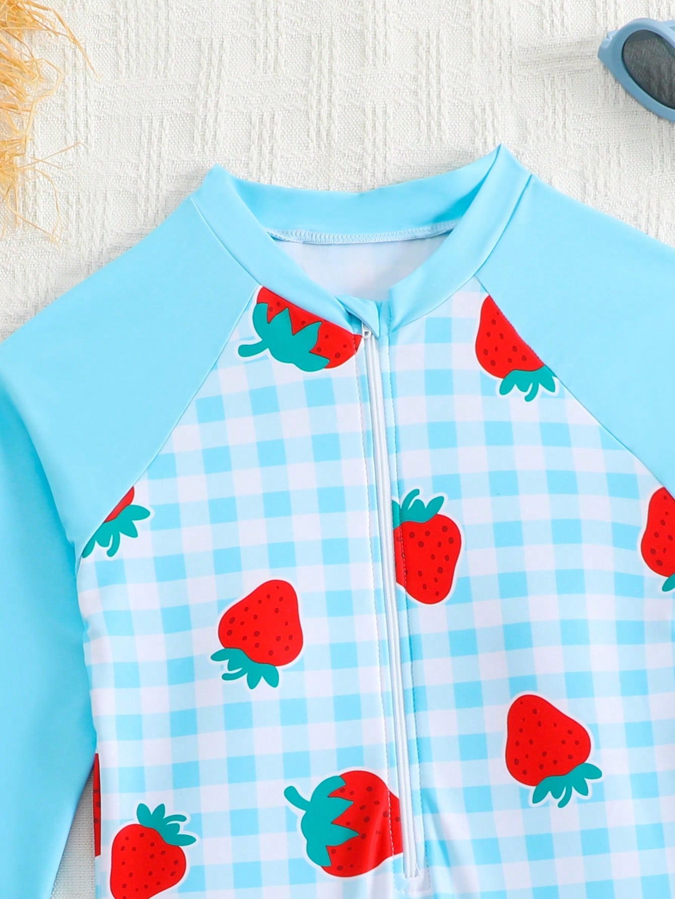 Tween girls one-piece swimsuit featuring a high neck, long sleeves, and shorts bottom, with a back zipper and strawberry plaid digital print on stretch knit fabric. Designed for swimming, vacation, and summer wear.