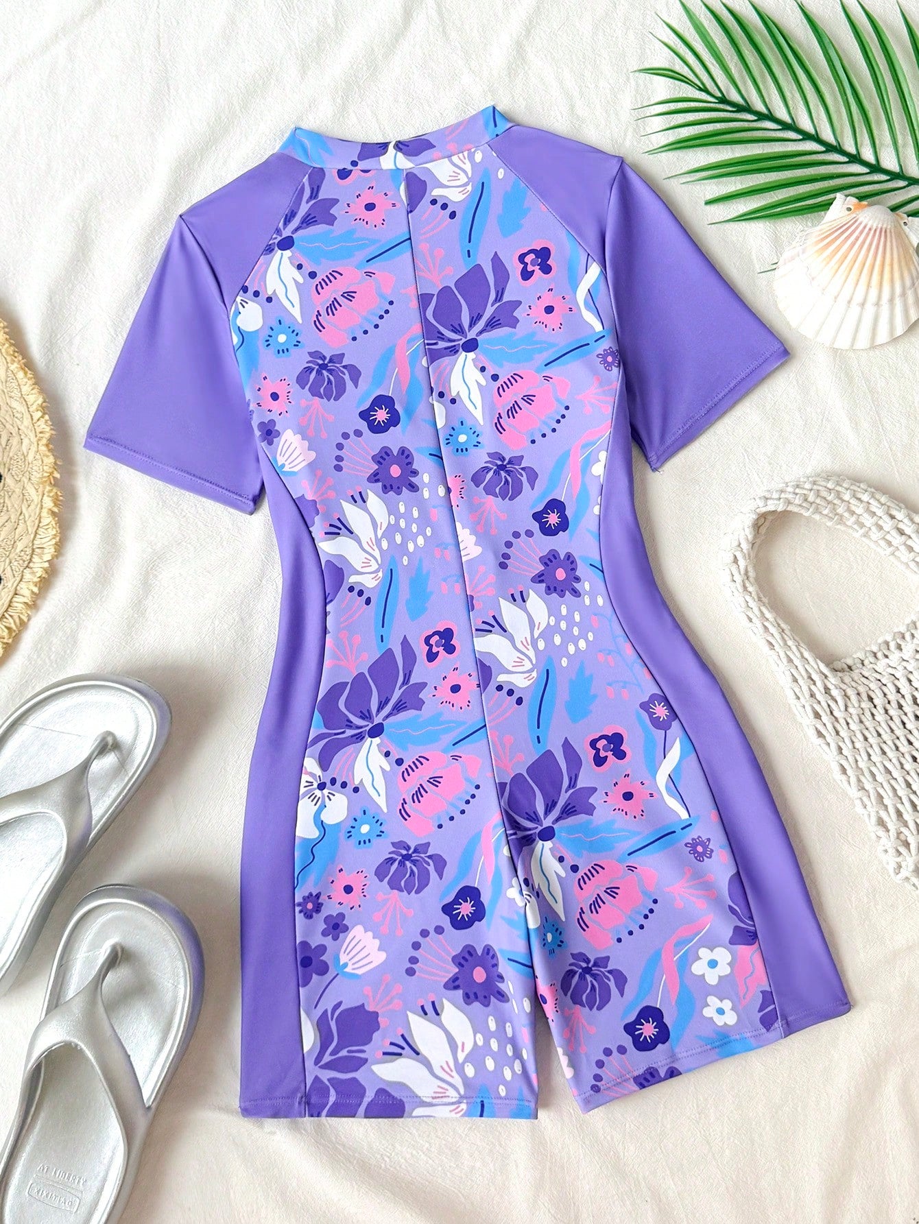 Black and white one-piece rashguard swimsuit for tween girls with short sleeves, high neck, zipper detail, fitted shape, and shorts-style bottom.