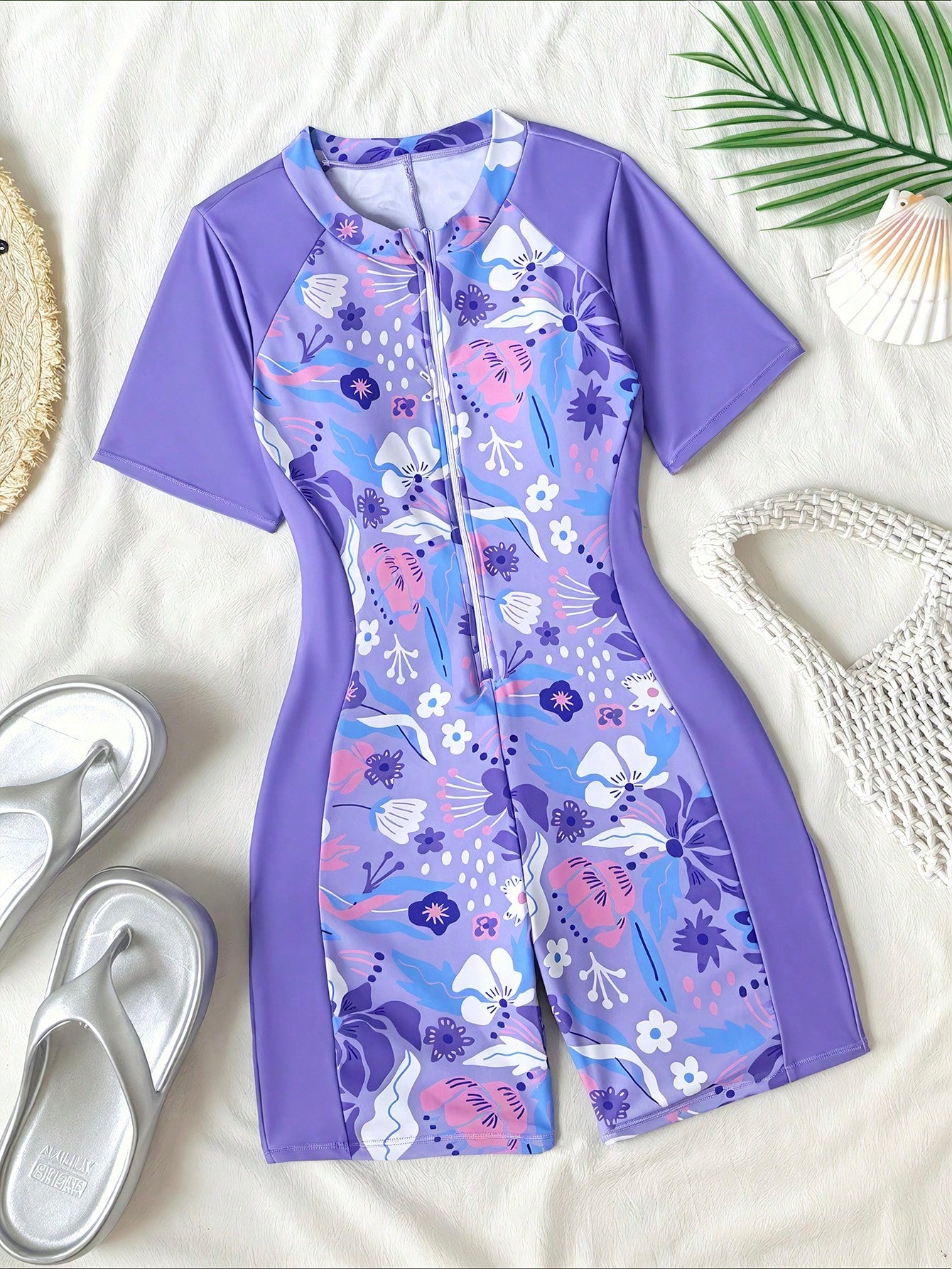 Black and white one-piece rashguard swimsuit for tween girls with short sleeves, high neck, zipper detail, fitted shape, and shorts-style bottom.