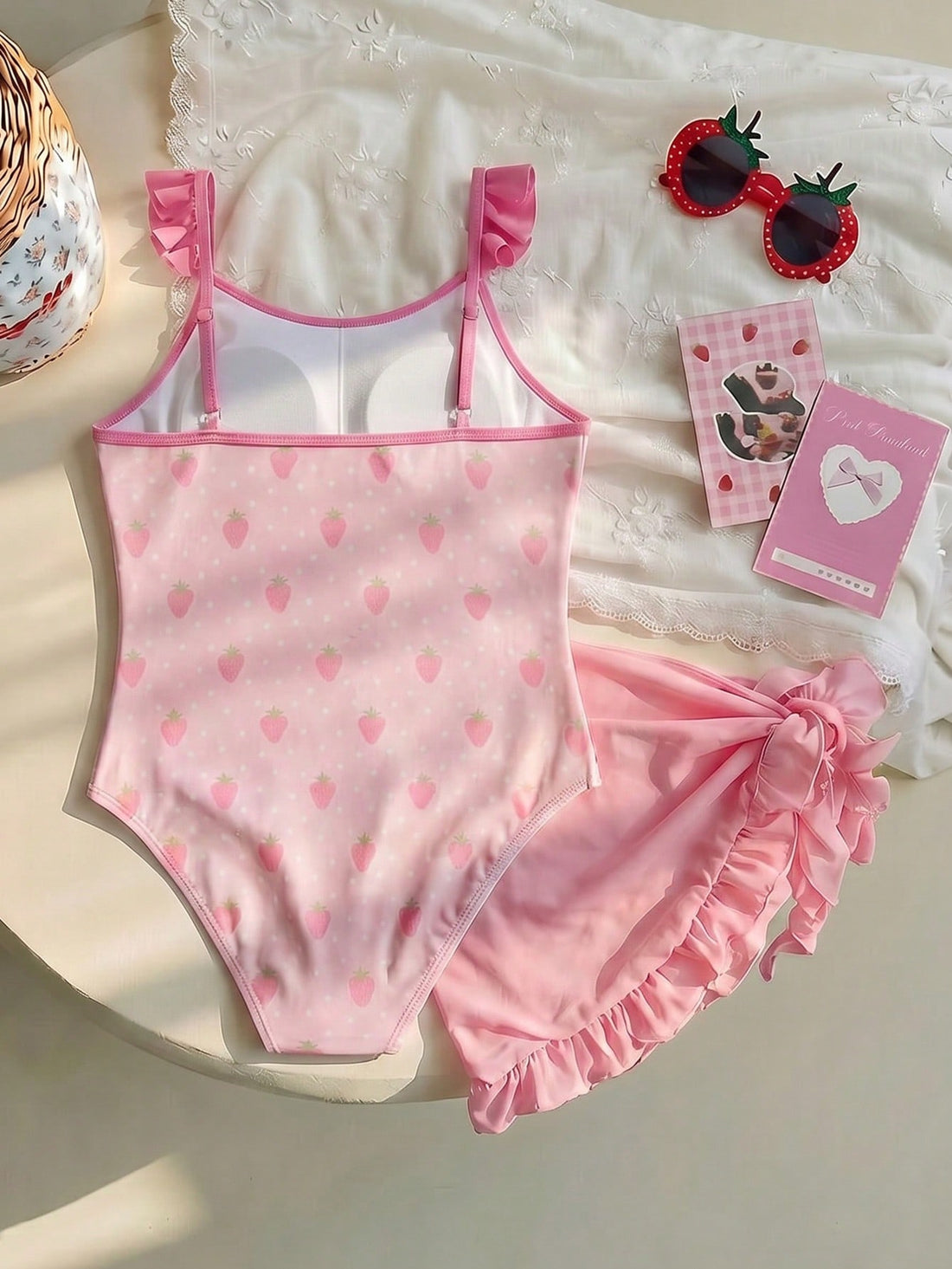 Pink tween girls one-piece swimsuit with ruffle details, spaghetti straps, plant pattern, and matching cover-up skirt set for summer beach wear