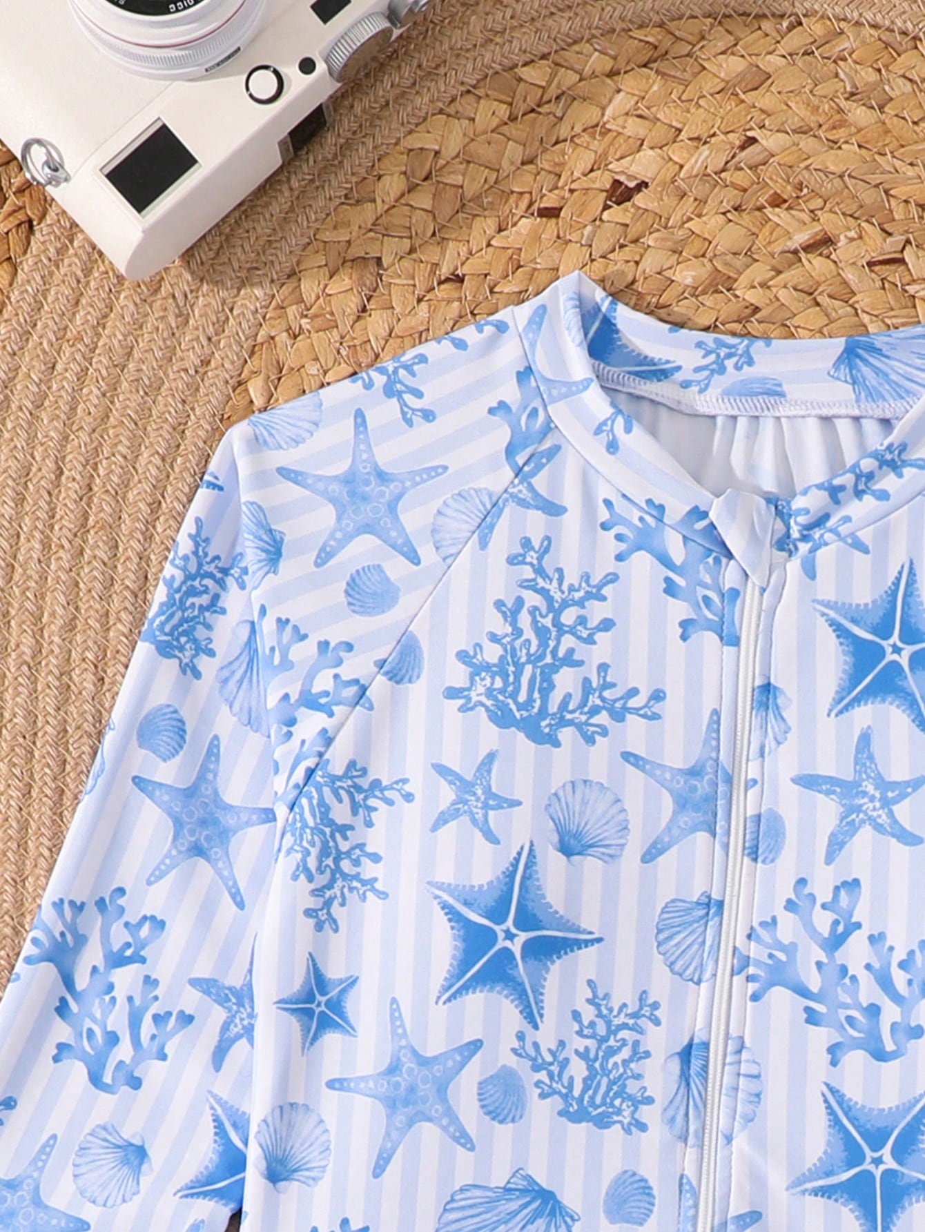Tween girls one-piece rash guard swimsuit with long sleeves, high neck, front zipper, and ocean shell graphic print in a fitted style for beach, swimming, and vacation wear.