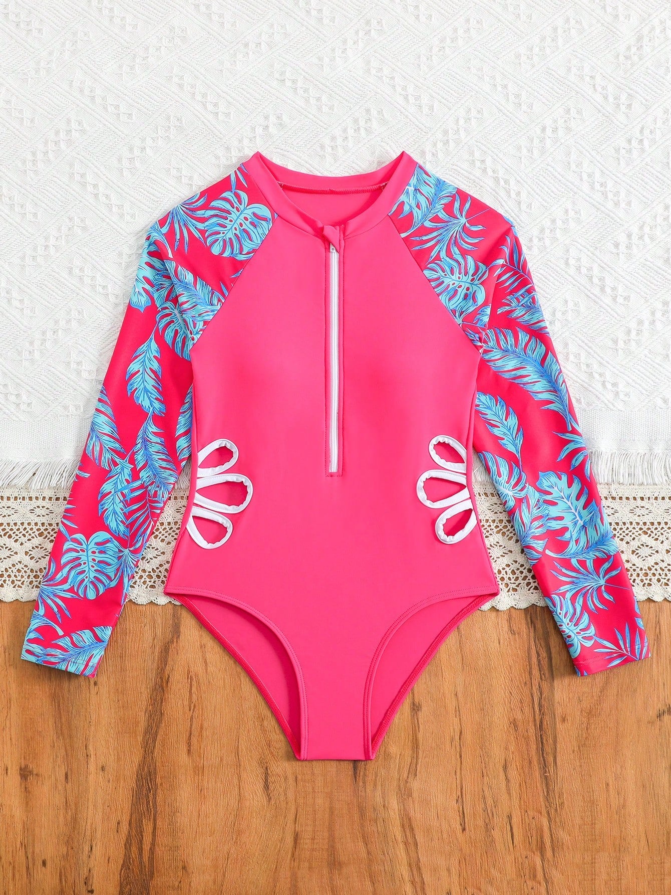 Tween girls one-piece rash guard swimsuit with long sleeves, high neck, front zipper, and ocean shell graphic print in a fitted style for beach, swimming, and vacation wear.