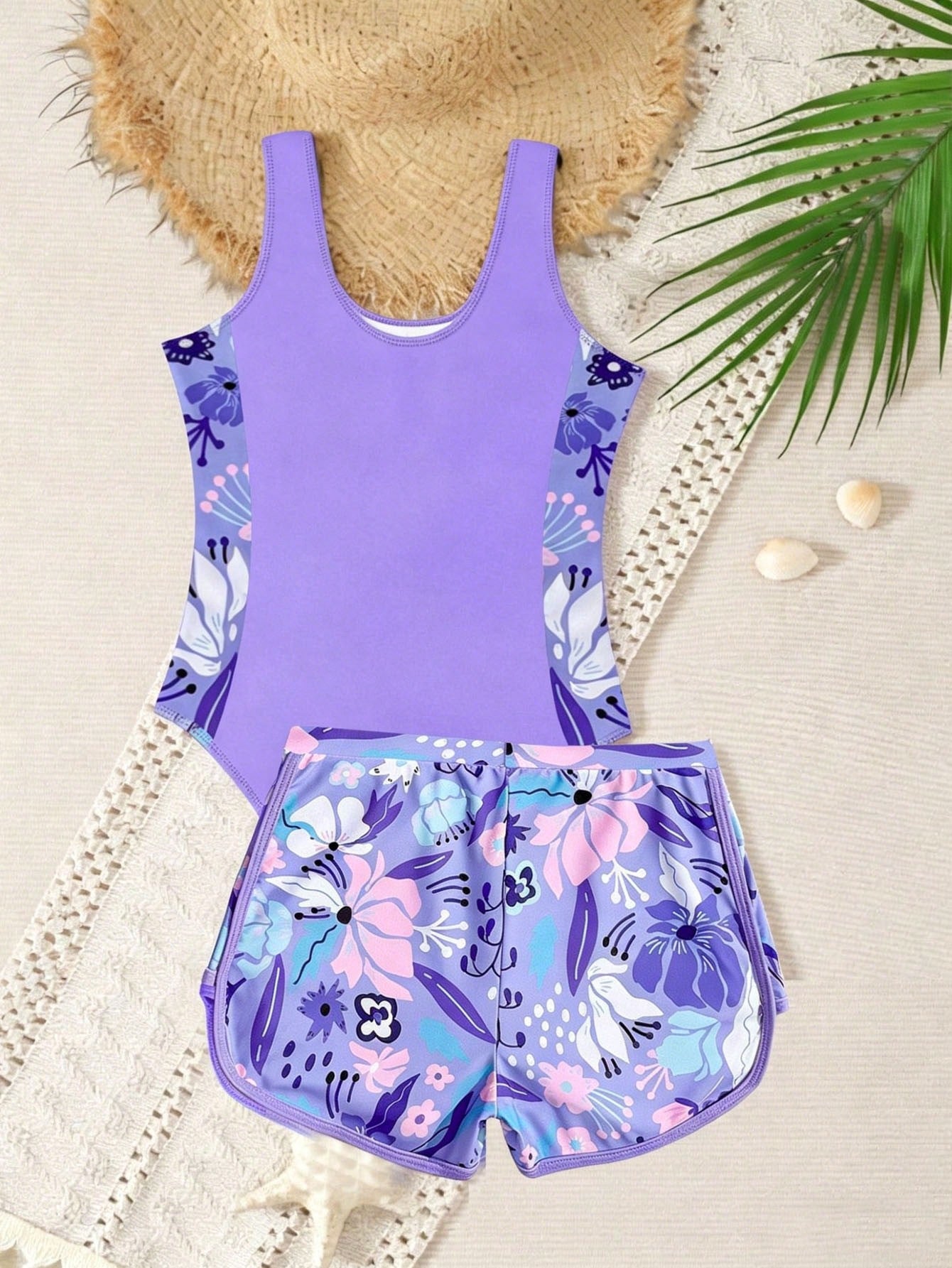 Tween girls 2-piece swimsuit set in black with full floral and plant print, featuring a sleeveless scoop-neck swim top and matching shorts-style bottoms.