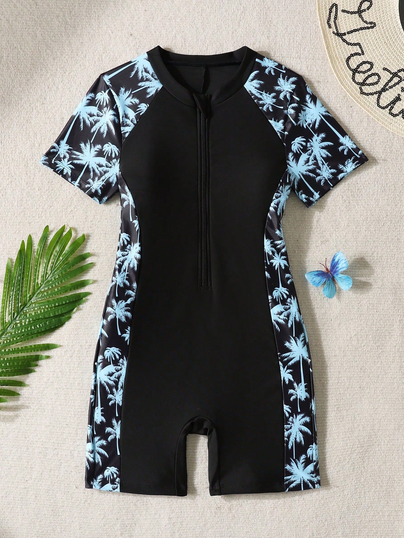 Black and white one-piece rashguard swimsuit for tween girls with short sleeves, high neck, zipper detail, fitted shape, and shorts-style bottom.