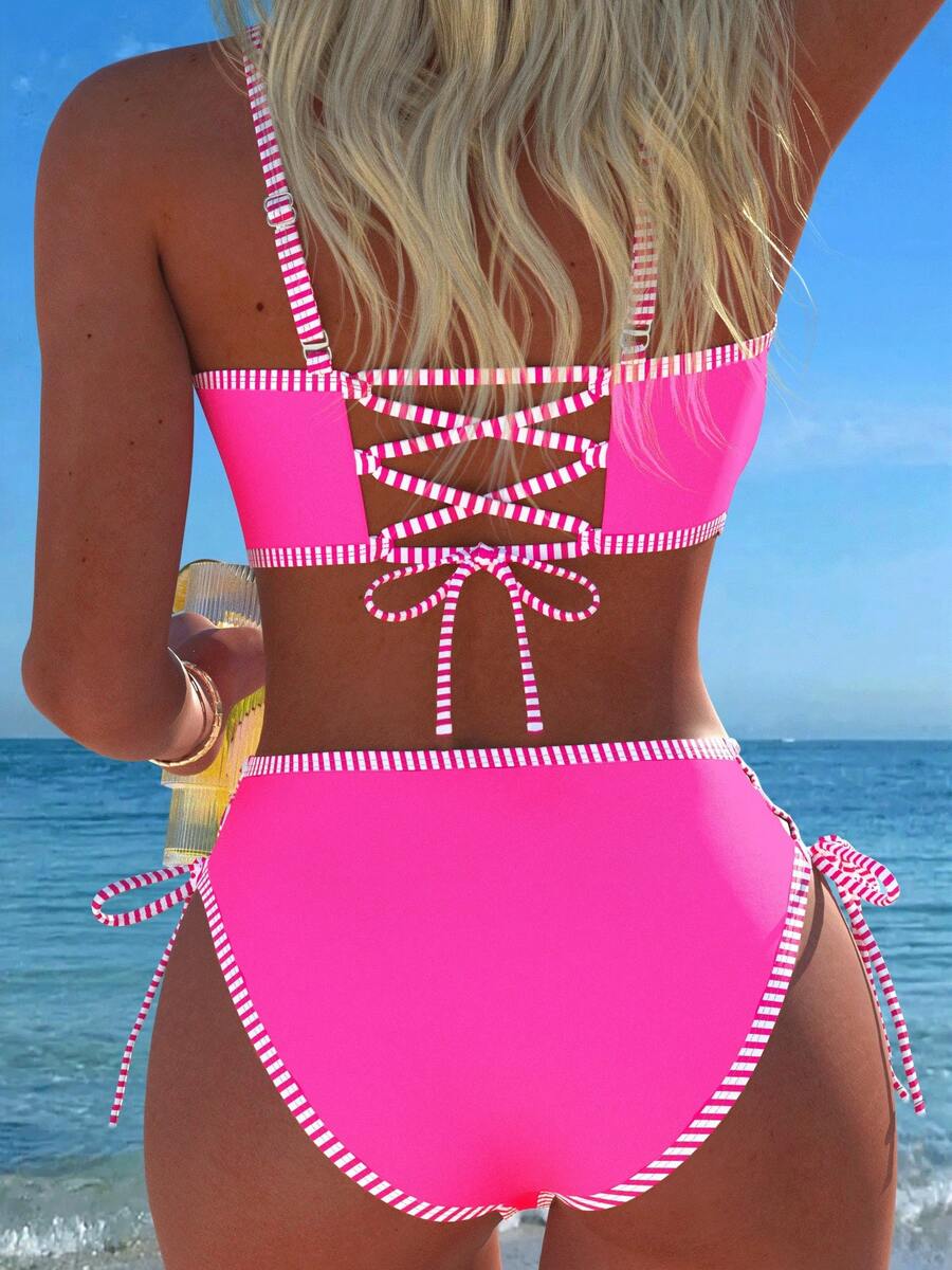 Women's hot pink split bikini set featuring a high waist tie-side bottom and a wireless bandeau top with criss cross details.
