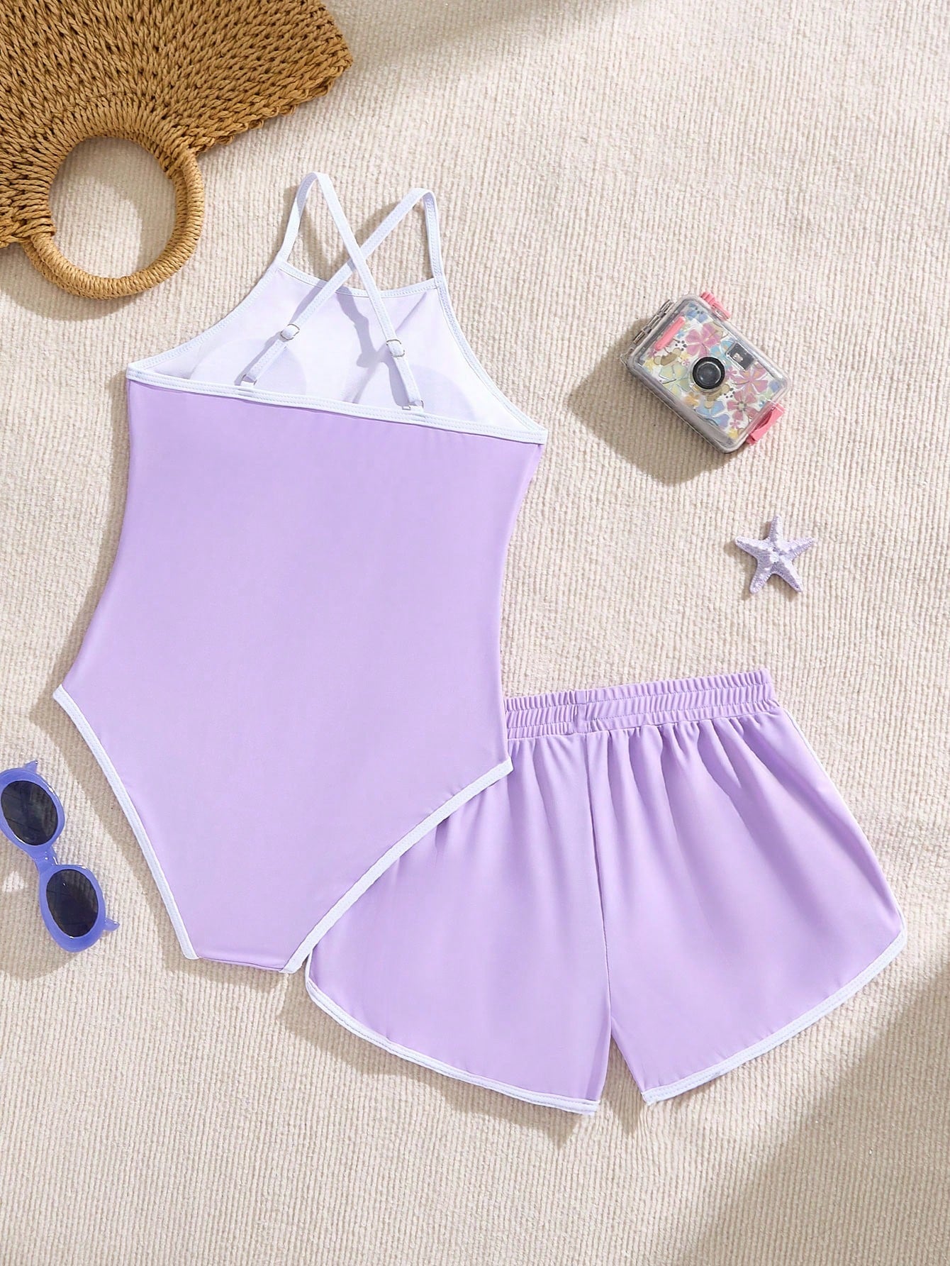 Girls' mauve purple one-piece swimsuit with swim shorts, spaghetti straps, contrast piping, letter pattern, and sleeveless vacation swimwear design.