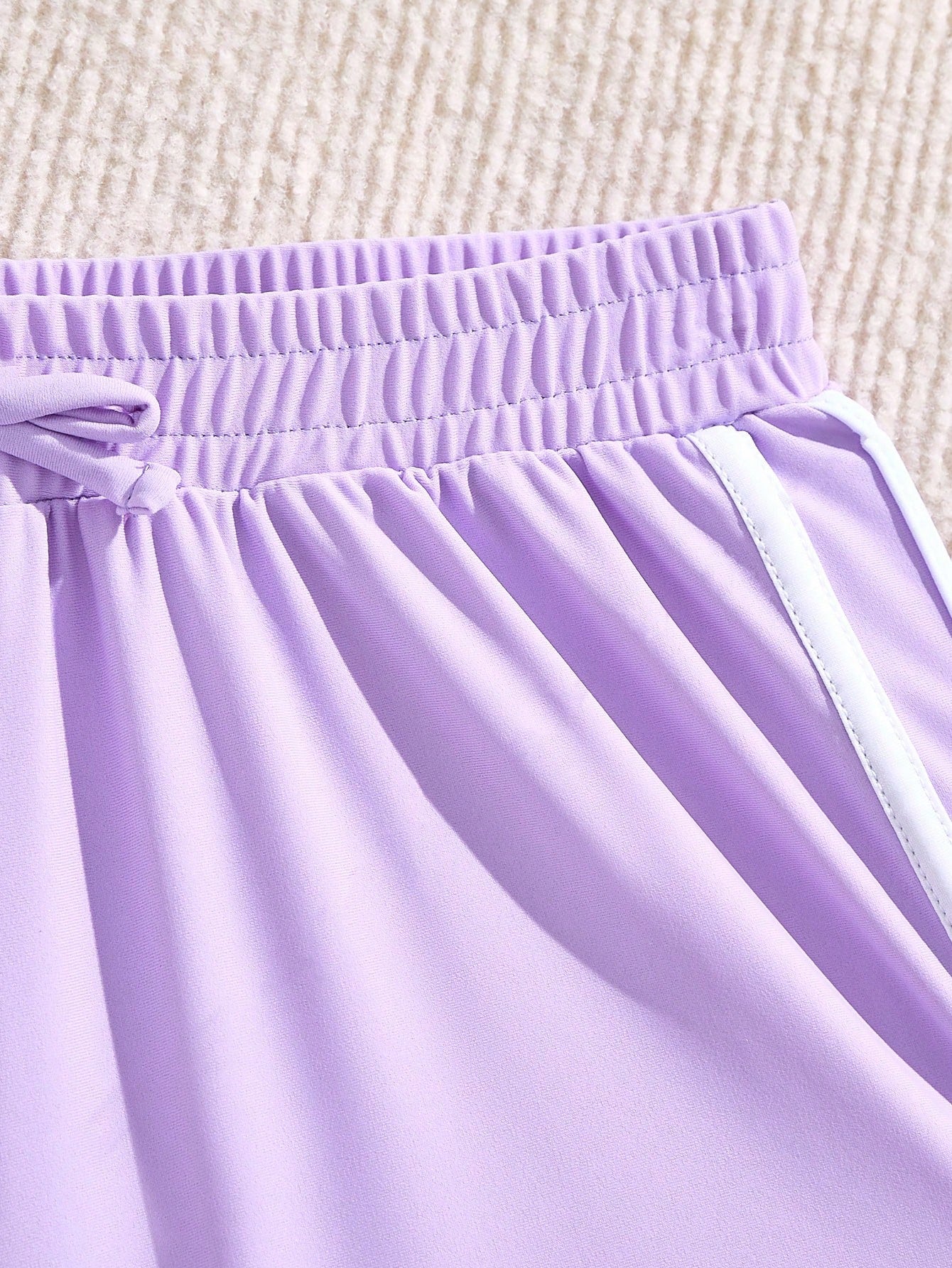Girls' mauve purple one-piece swimsuit with swim shorts, spaghetti straps, contrast piping, letter pattern, and sleeveless vacation swimwear design.