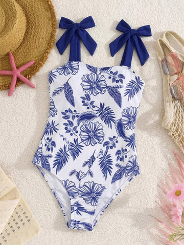 Navy blue tween girls one-piece swimsuit with all-over floral print, bow decor, strap neckline, and shorts-style bottom for summer vacation beachwear.