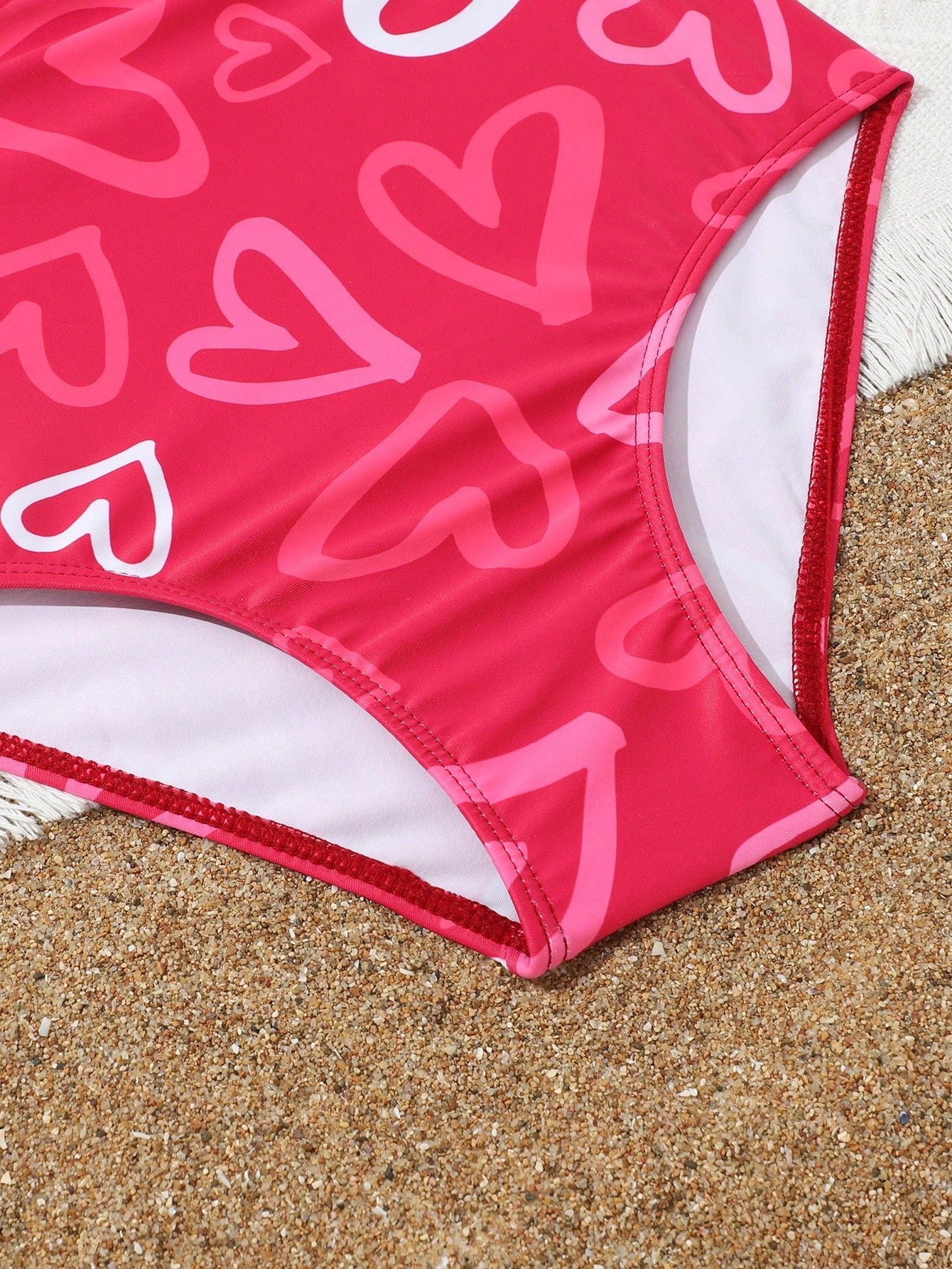 Tween girl multicolor one-piece swimsuit with gradient heart graphic print, scoop neck, cutout detail, and fitted vacation beachwear style.