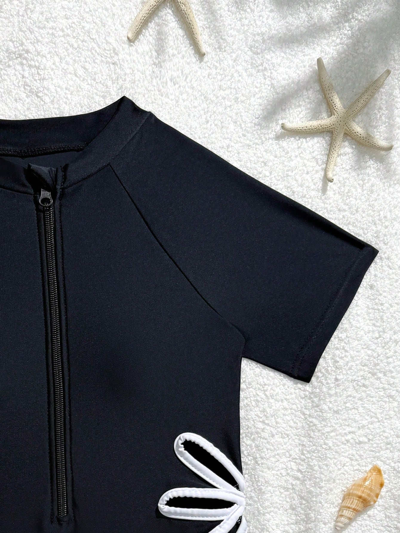 Black tween girls one-piece swimsuit with zipper front, short sleeves, high neck, hollow-out detail, and shorts-style bottom for beach, pool, surfing, and swimming.