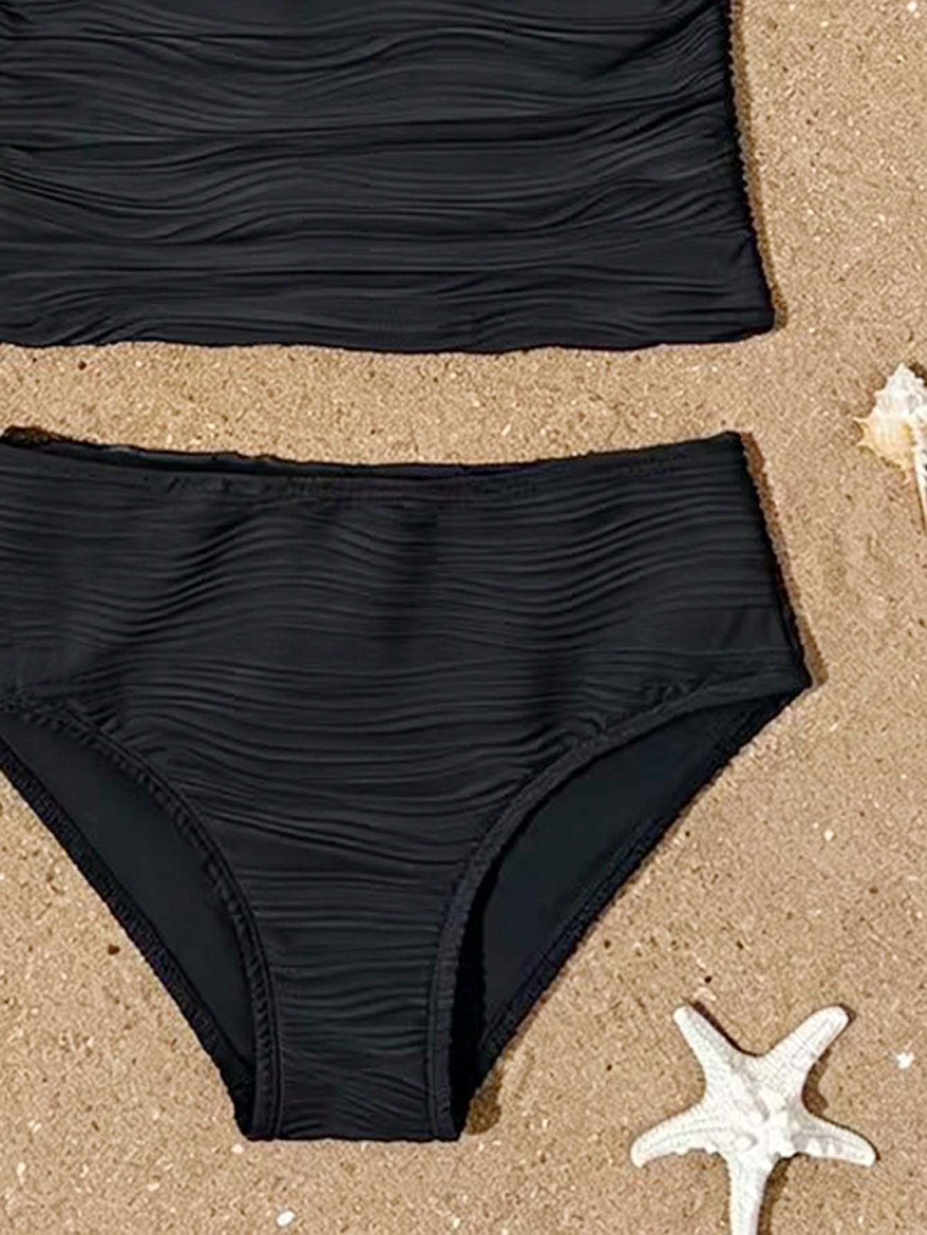 Tween girls 2-piece bikini swimwear set in black with a wave-pattern geometric design, featuring halter neckline, wireless top, and high-waist short bottoms with starfish and shell decor.