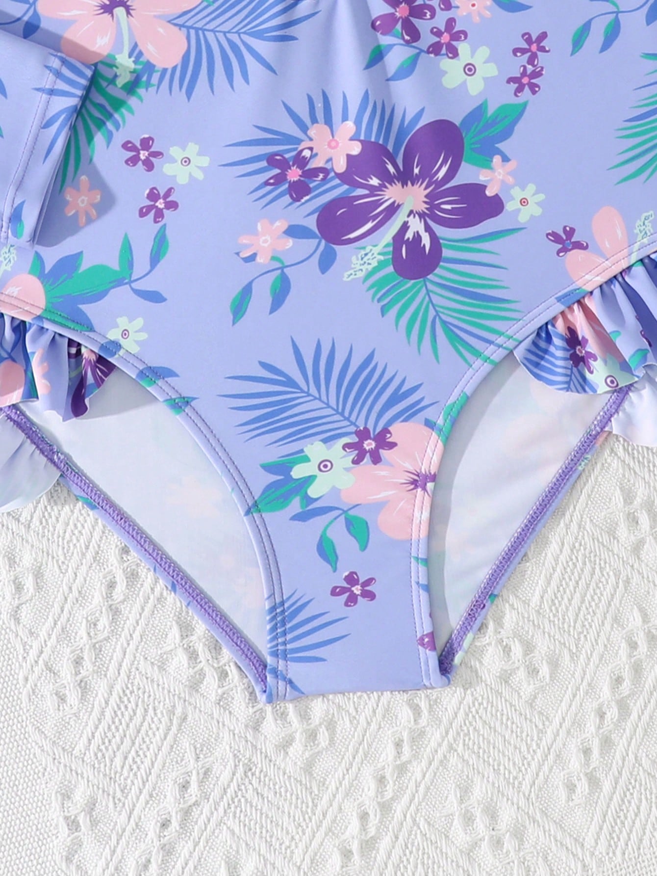 Girls one-piece swimsuit in blue with all-over leopard leaf print, ruffle detail, zipper front, high neck, and lined body for swimming and vacation.