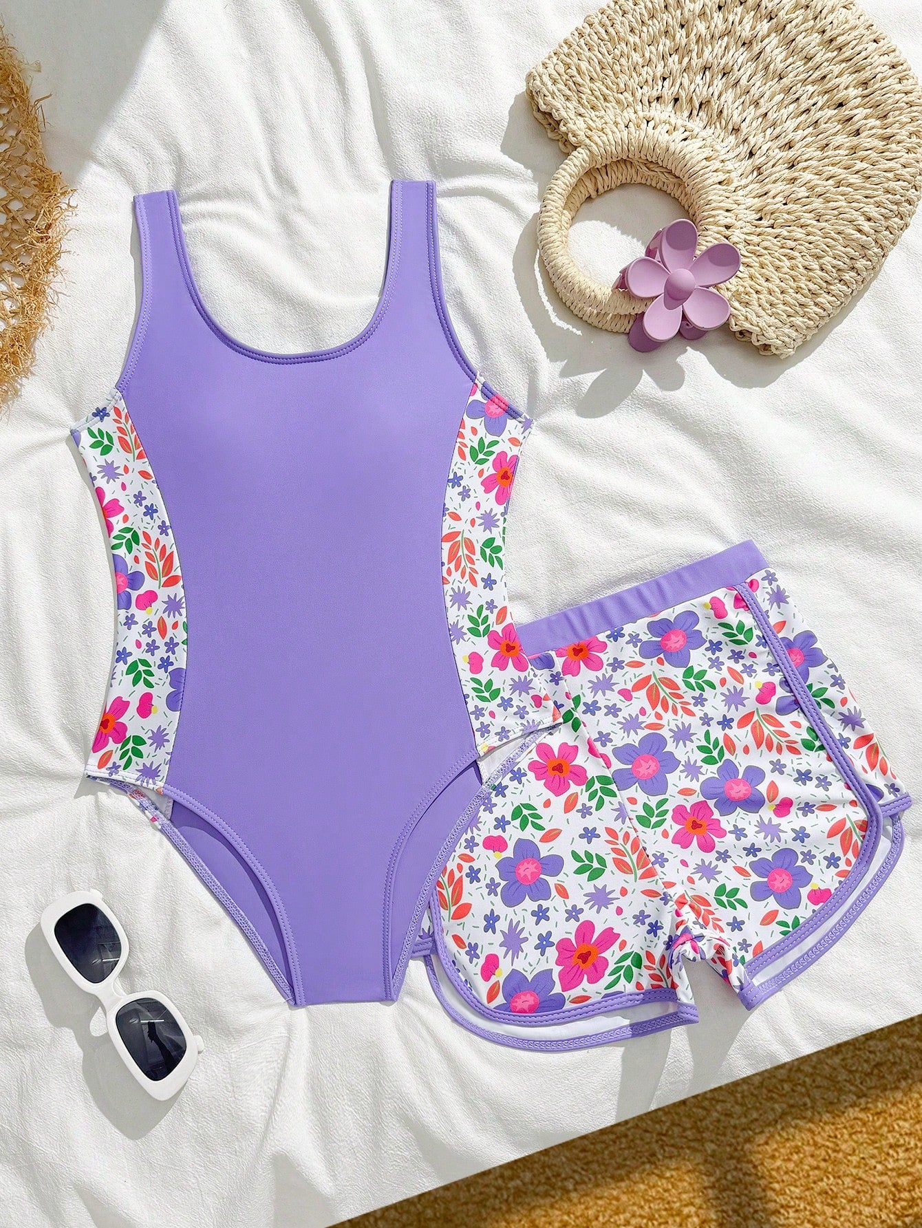 Tween girls 2-piece swimsuit set in black with full floral and plant print, featuring a sleeveless scoop-neck swim top and matching shorts-style bottoms.