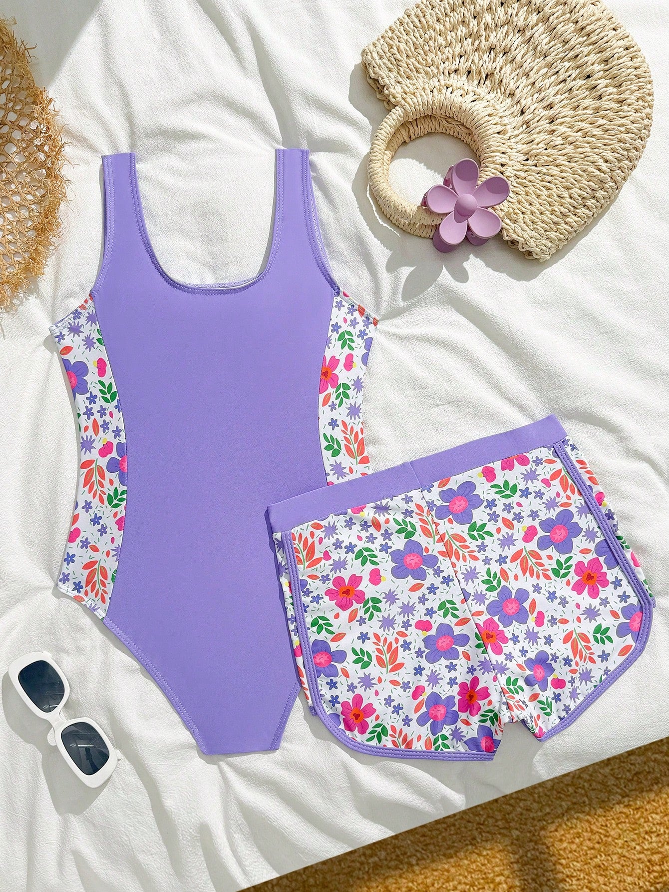 Tween girls 2-piece swimsuit set in black with full floral and plant print, featuring a sleeveless scoop-neck swim top and matching shorts-style bottoms.