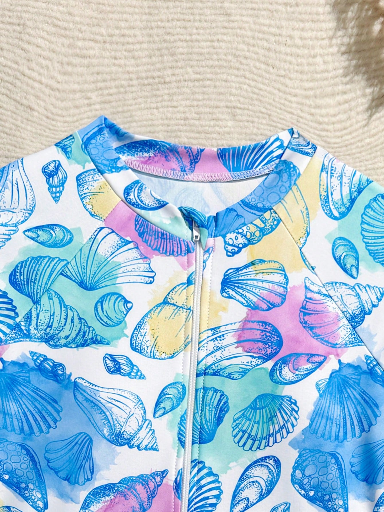Girls one-piece swimsuit in blue with all-over leopard leaf print, ruffle detail, zipper front, high neck, and lined body for swimming and vacation.