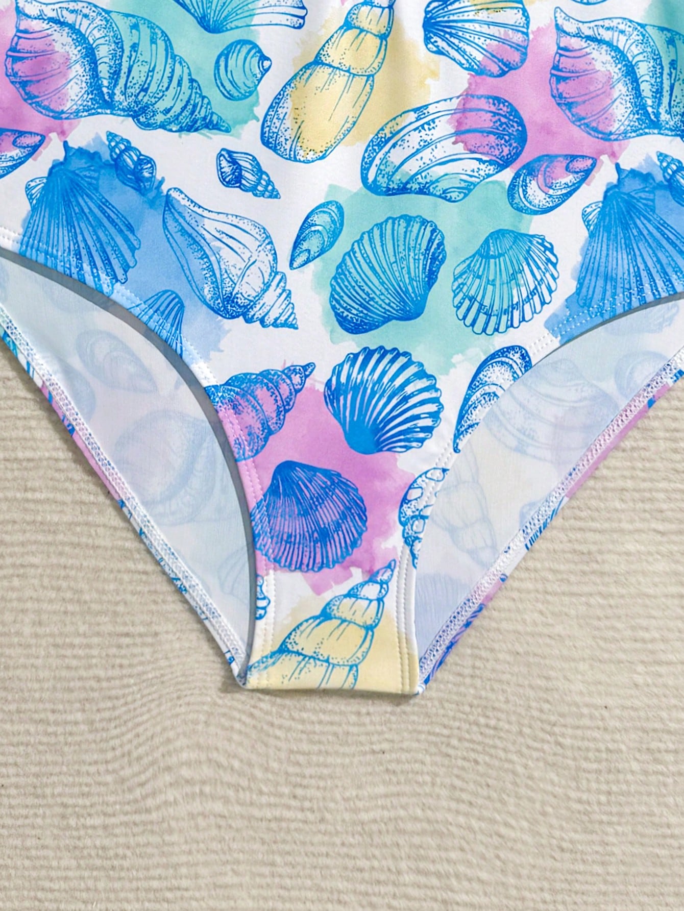 Girls one-piece swimsuit in blue with all-over leopard leaf print, ruffle detail, zipper front, high neck, and lined body for swimming and vacation.