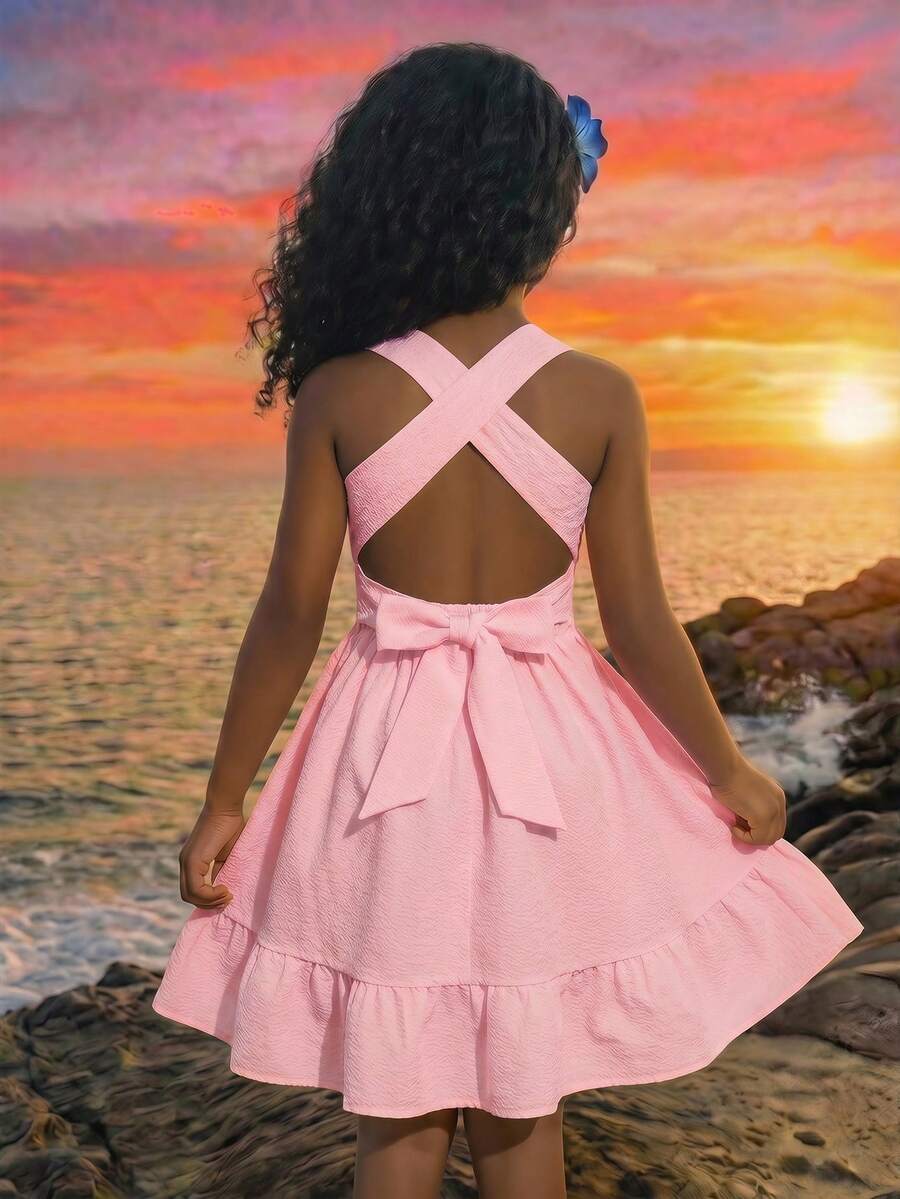 Pink sleeveless tween girls vacation dress with all-over fruit and vegetable print, strap neckline, belted high waist, cut-out detail, and flared ruffle hem.