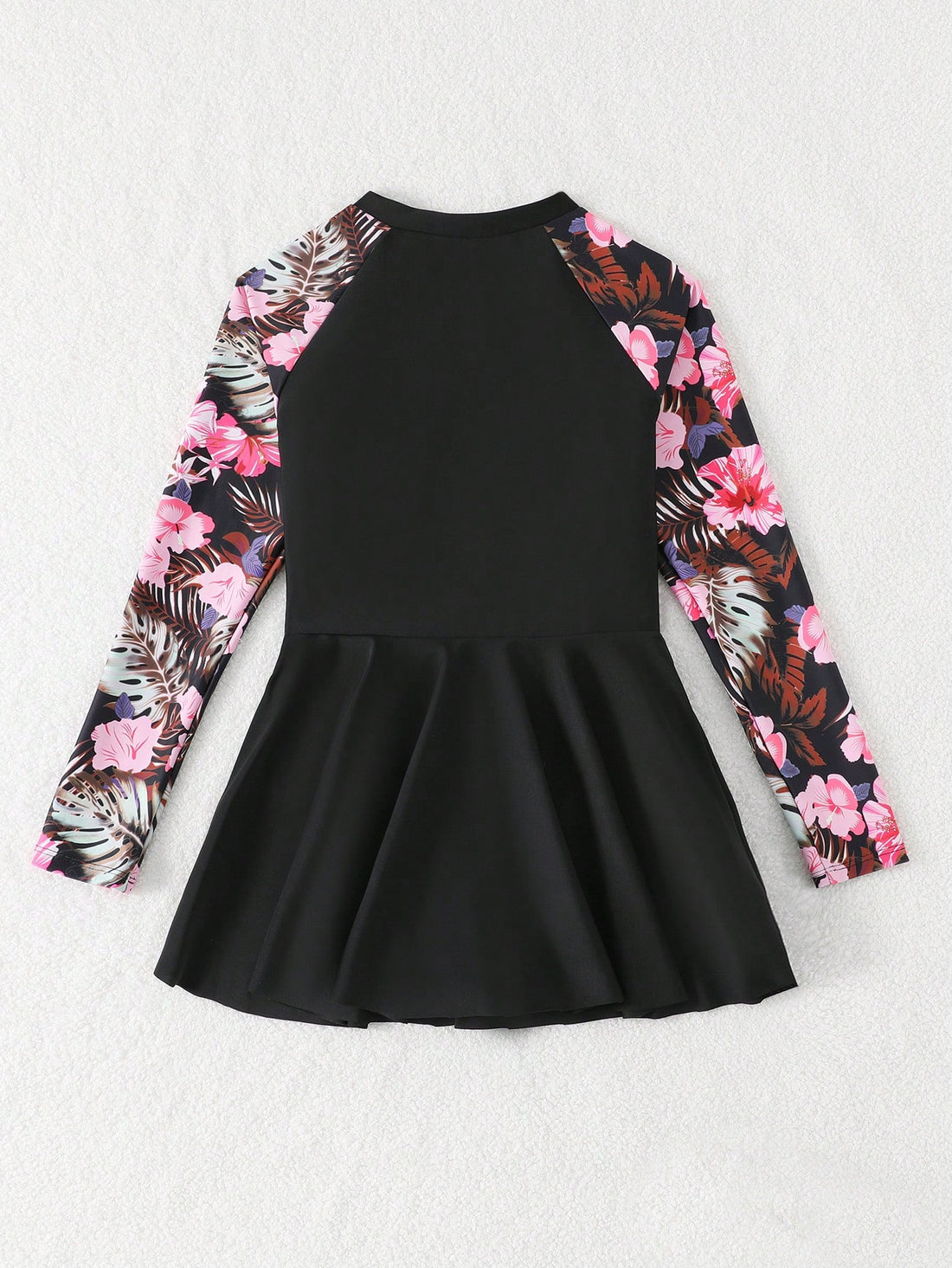 Tween girls one-piece swimsuit in black floral pattern with long sleeves, high neck, front zipper, and a skirt-style bottom.
