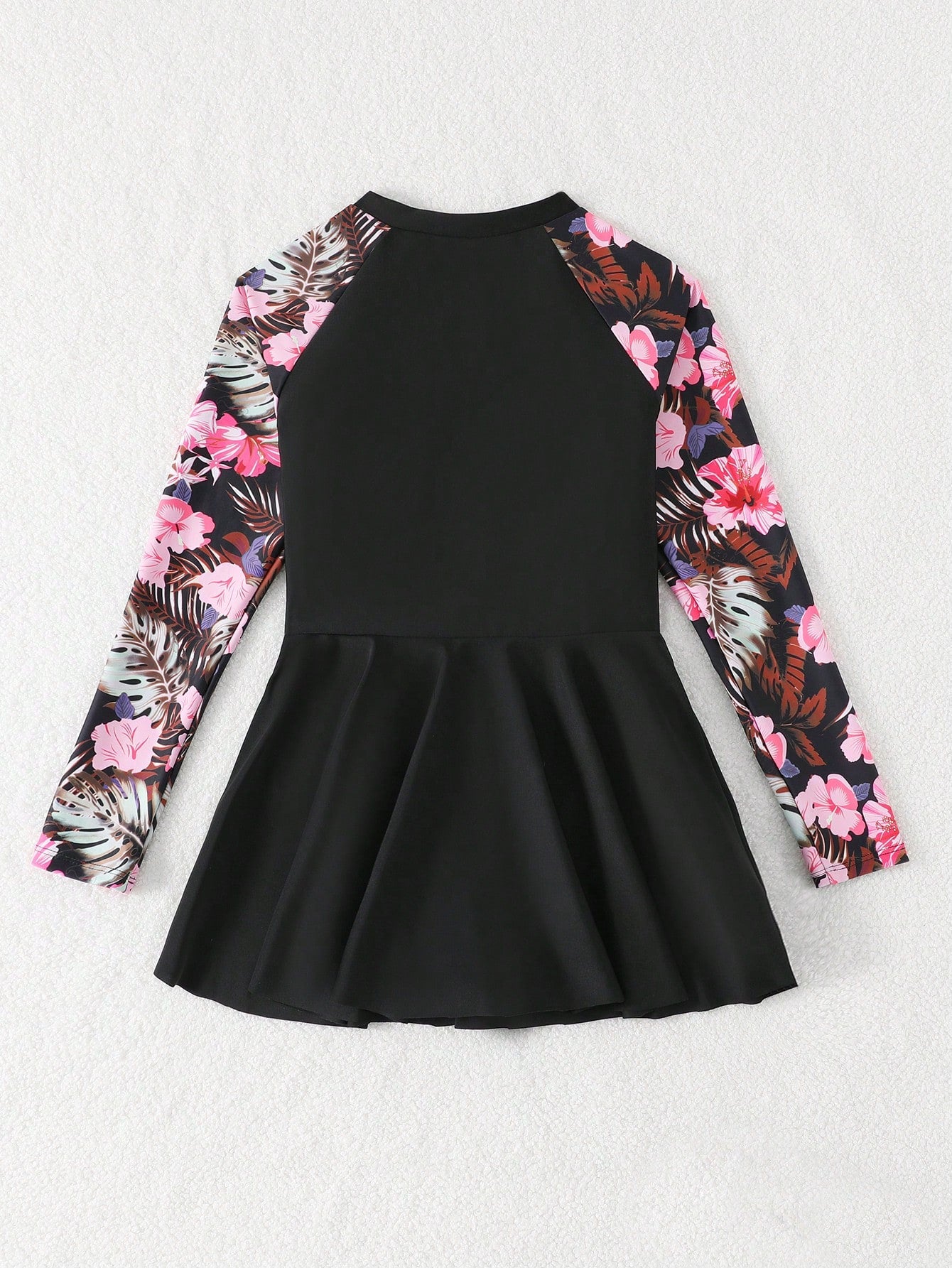Tween girls one-piece swimsuit in black floral pattern with long sleeves, high neck, front zipper, and a skirt-style bottom.