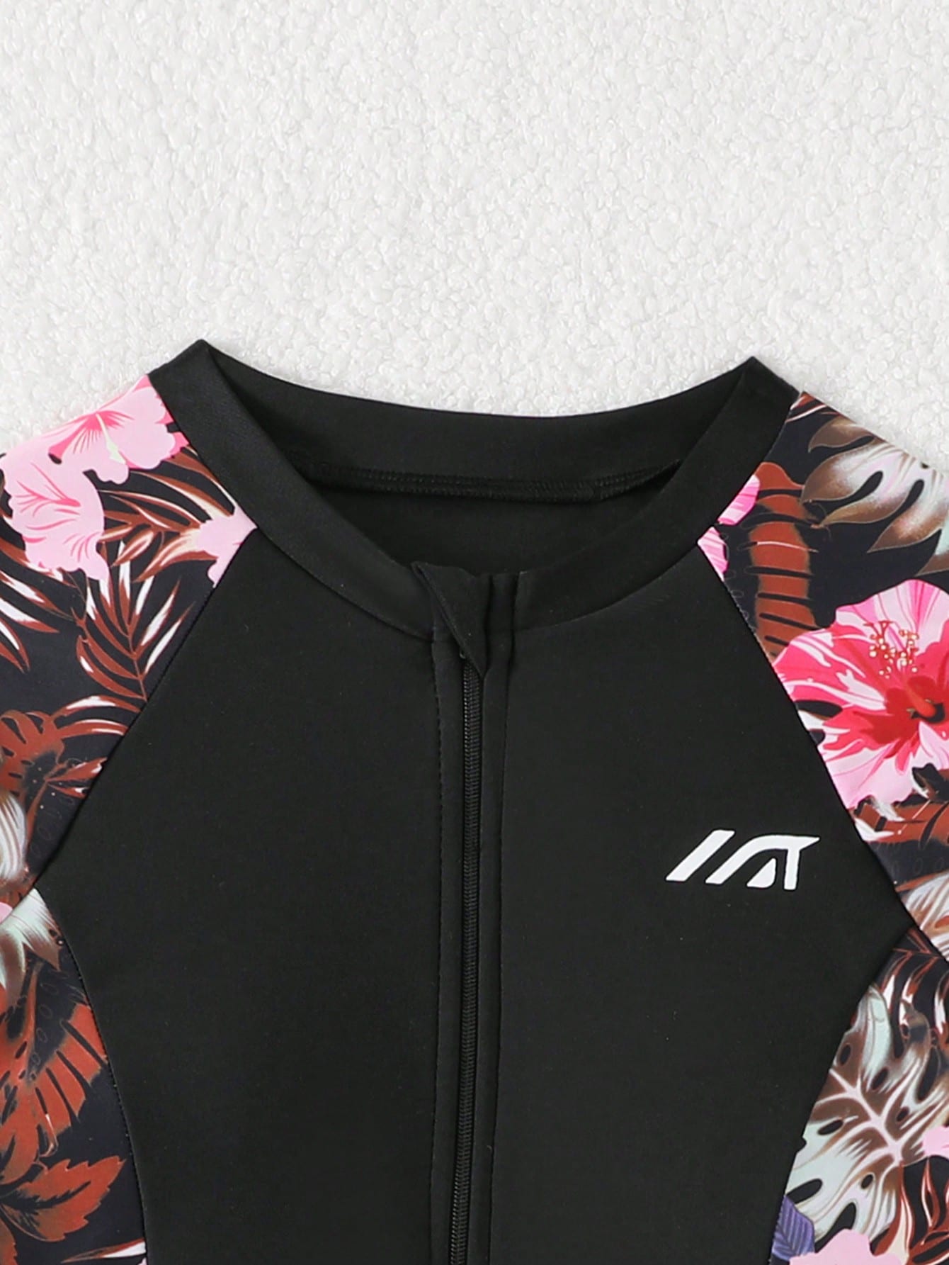 Tween girls one-piece swimsuit in black floral pattern with long sleeves, high neck, front zipper, and a skirt-style bottom.