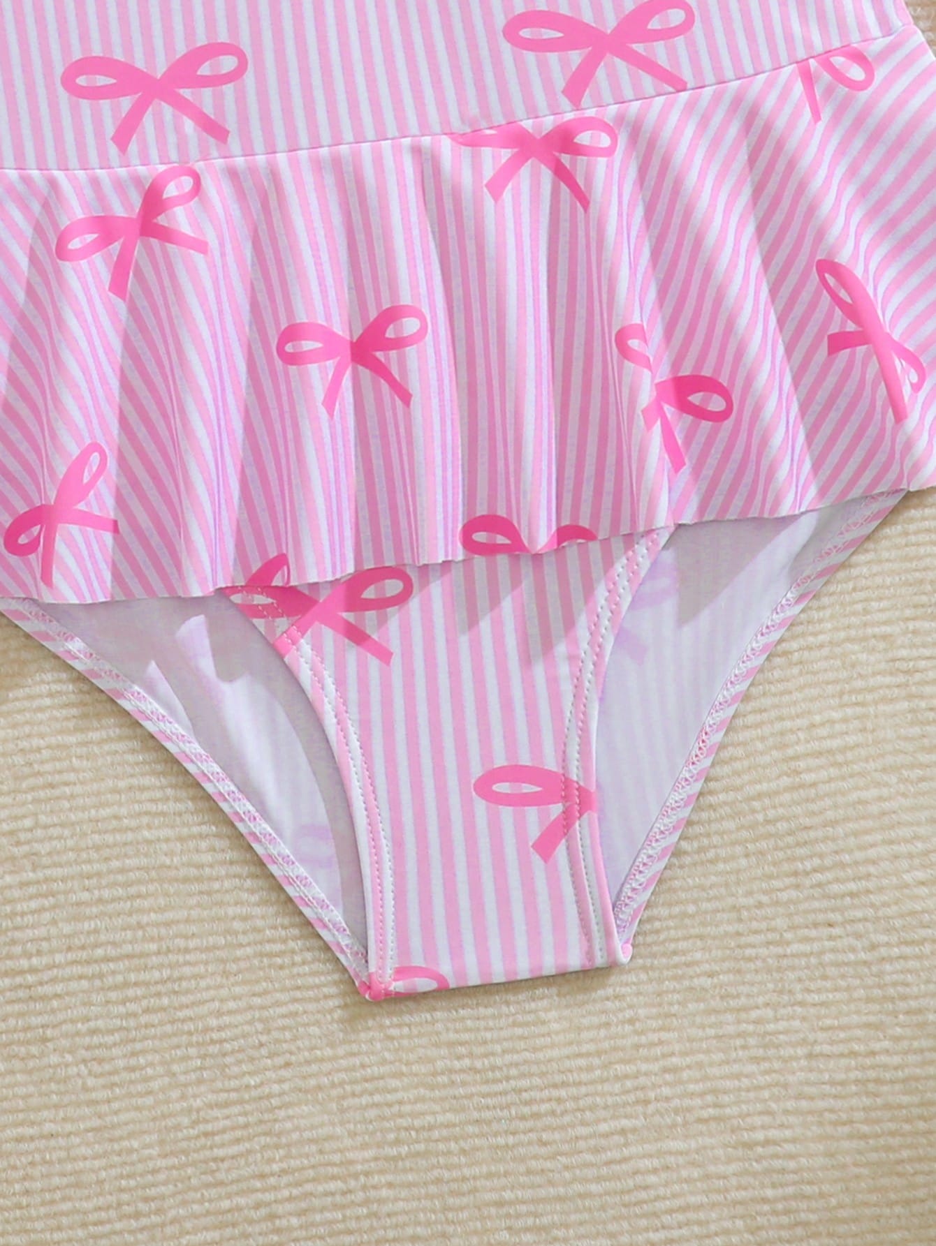 Purple tween girls one-piece swimsuit with graphic striped print, ruffle detail, round neck, and zipper closure for swimming and vacation wear