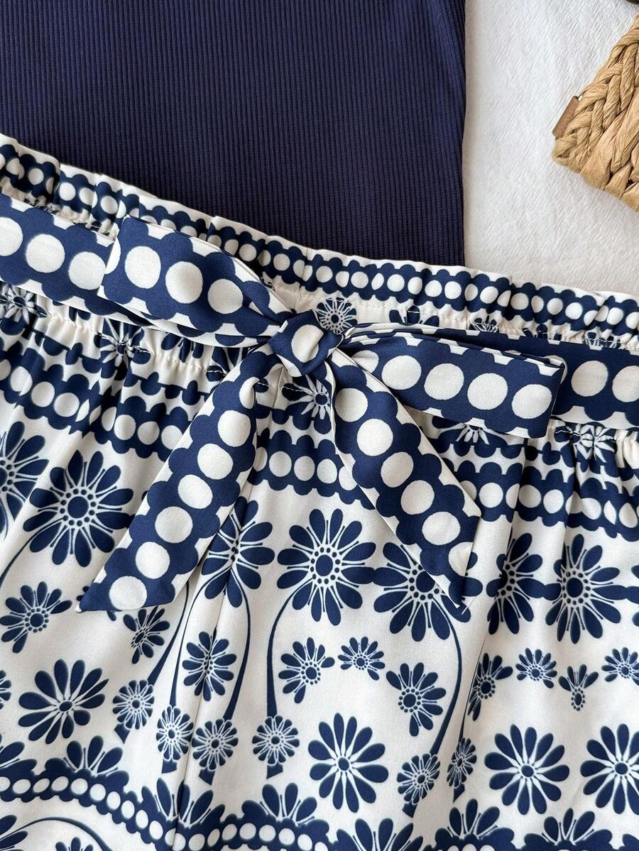 Tween girl summer two-piece outfit featuring a white scoop neck tank top and green ditsy floral print paperbag waist shorts with belt.