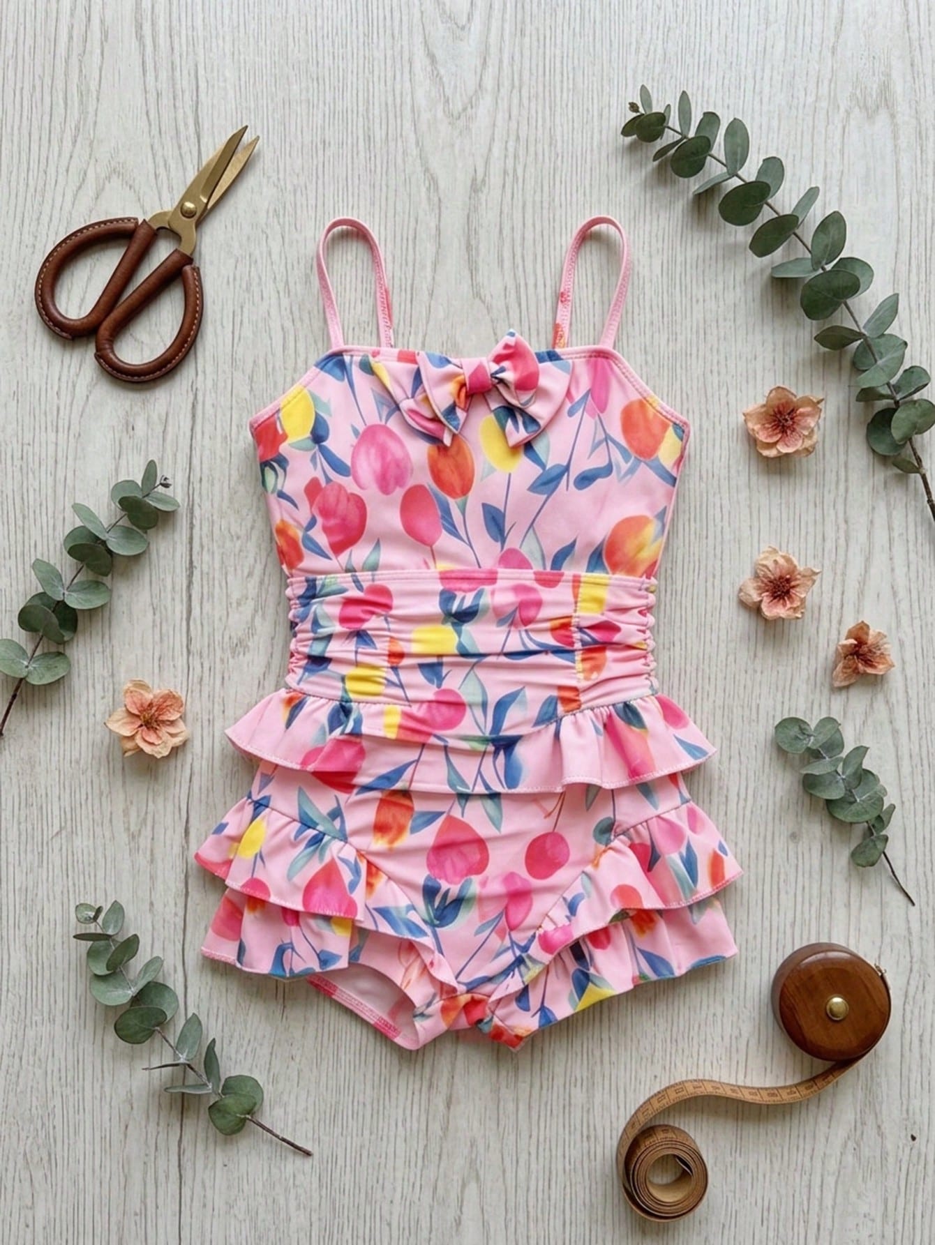 Pink one-piece swimsuit for tween girls with ruffle details, spaghetti straps, all-over print, and mid-waist bottom