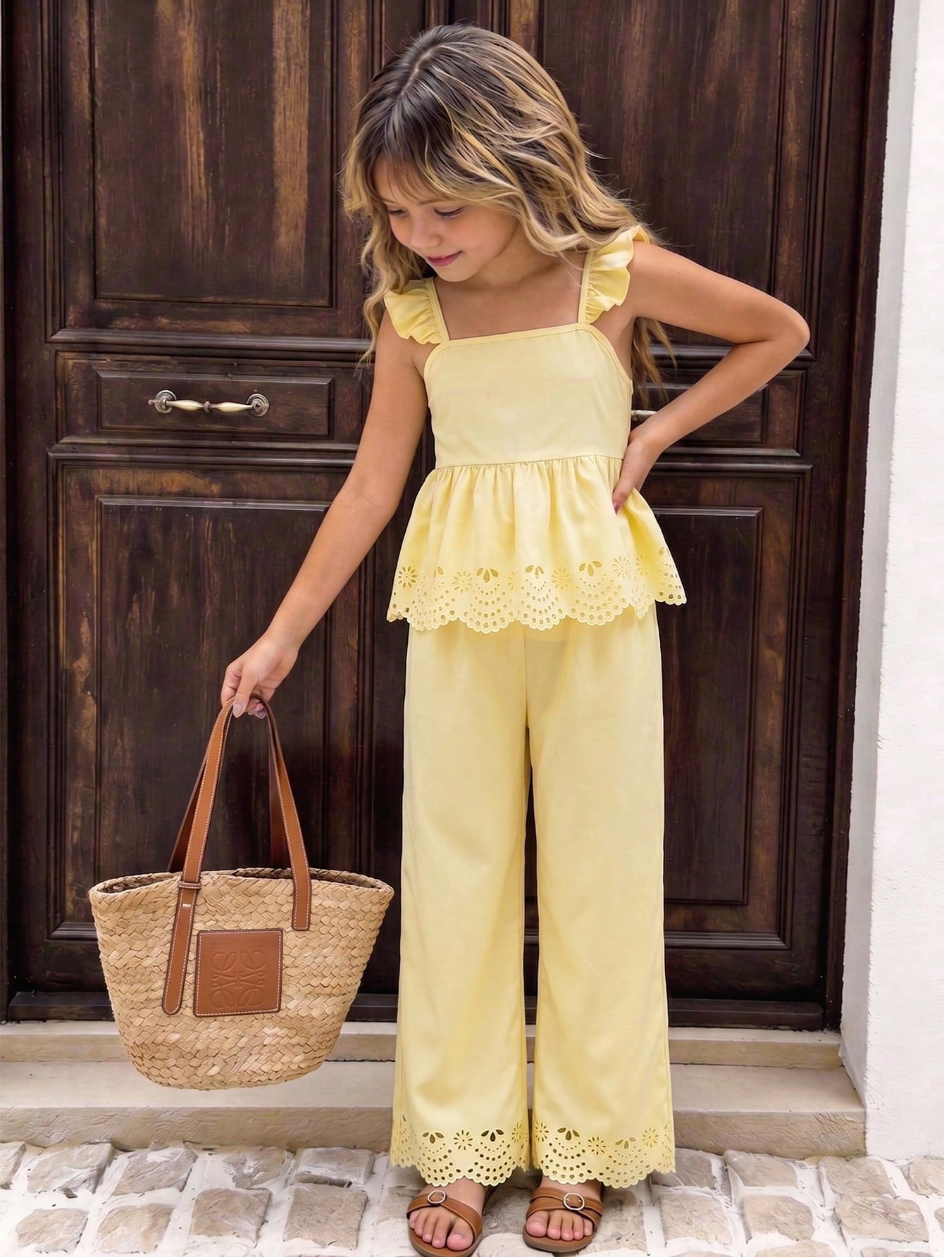 Tween girl wearing an apricot 2-piece outfit set featuring a shirred spaghetti strap short cami top and matching wide-leg long pants.