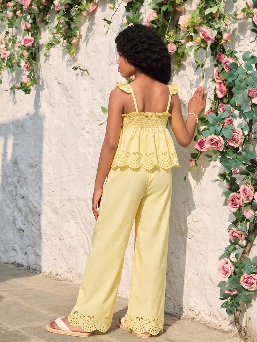 Tween girl wearing an apricot 2-piece outfit set featuring a shirred spaghetti strap short cami top and matching wide-leg long pants.