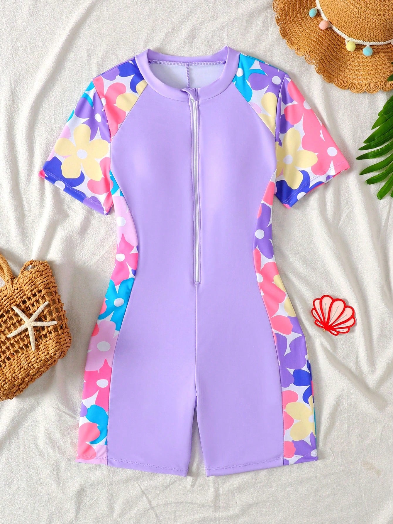 Black and white one-piece rashguard swimsuit for tween girls with short sleeves, high neck, zipper detail, fitted shape, and shorts-style bottom.