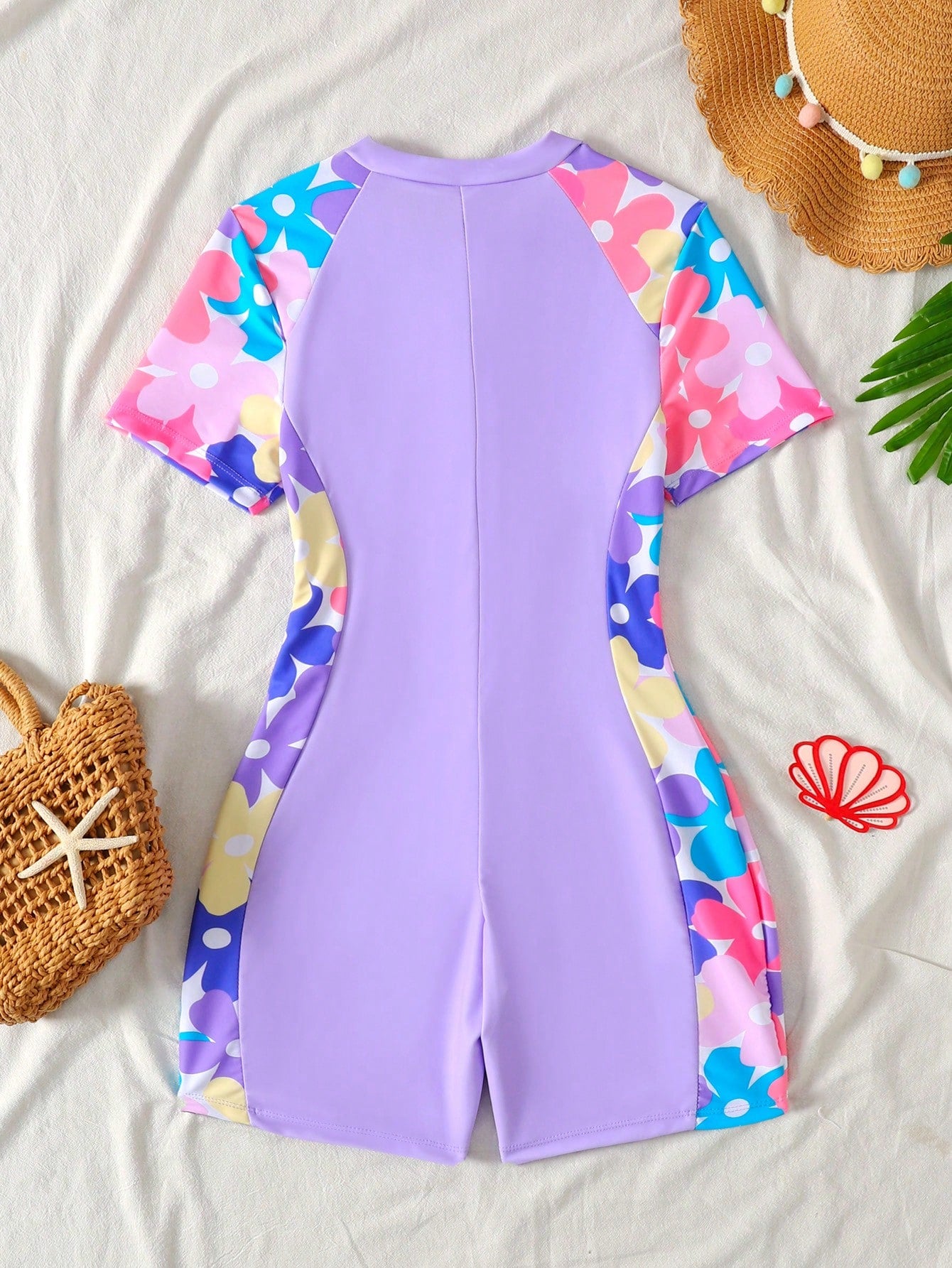 Black and white one-piece rashguard swimsuit for tween girls with short sleeves, high neck, zipper detail, fitted shape, and shorts-style bottom.