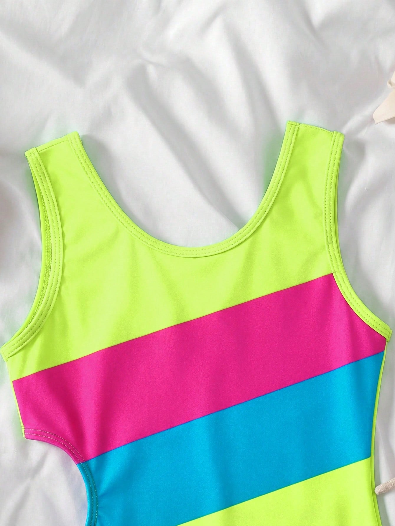 Tween girls' black and white one-piece swimsuit with striped patchwork design, scoop neck, asymmetrical cut-out detail, and fitted vacation swimwear style.
