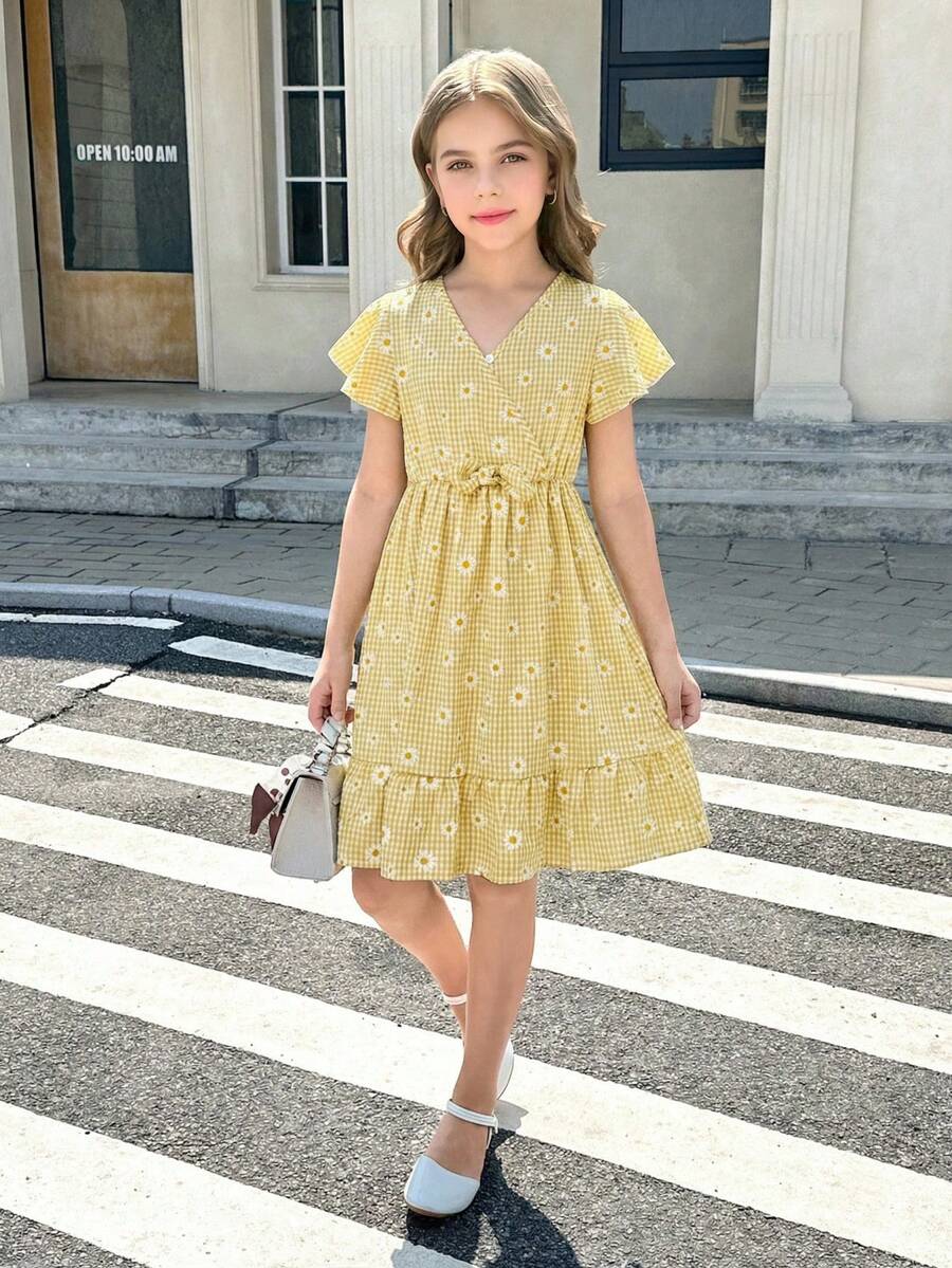 Tween girl wearing a black ditsy floral A-line short dress with V-neckline and flounce short sleeves.