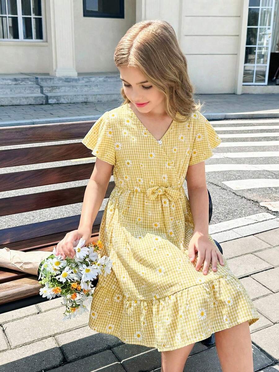 Tween girl wearing a black ditsy floral A-line short dress with V-neckline and flounce short sleeves.