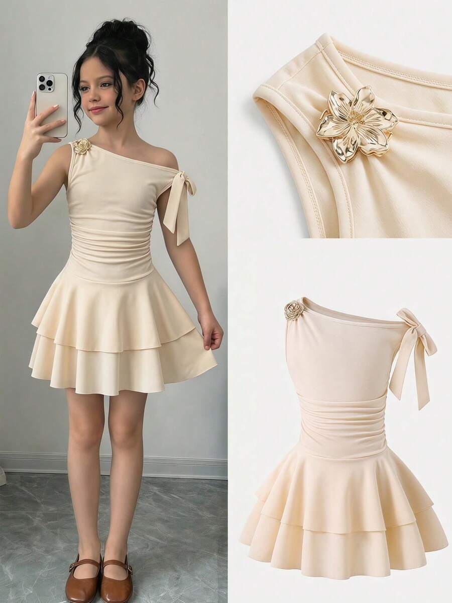 Tween girl wearing an apricot asymmetric skater dress with ruffle and applique details for party and formal occasions.