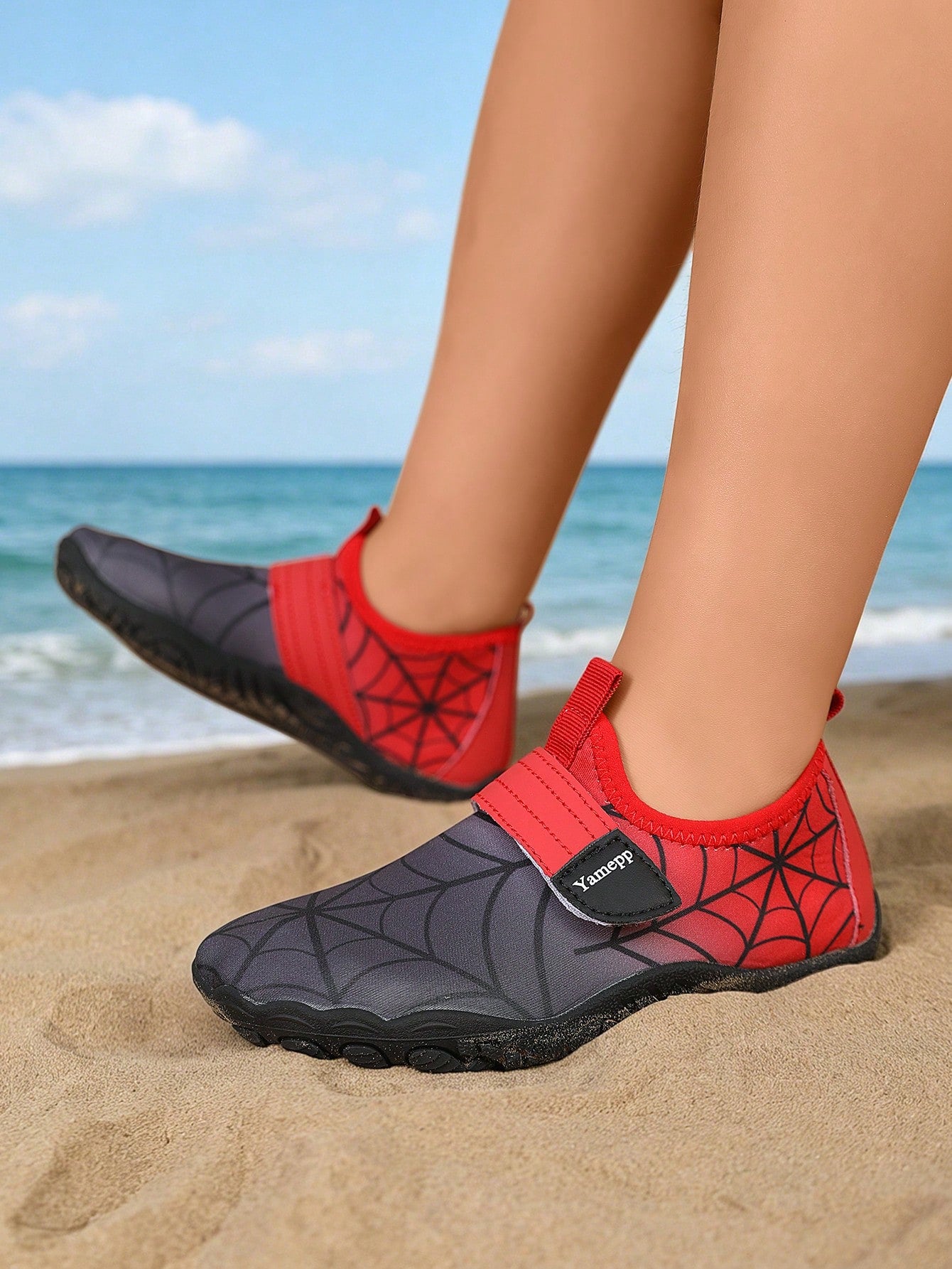 Black kids water shoes featuring a spider web graphic design, fabric upper, hook loop closure, and non-slip rubber outsole.